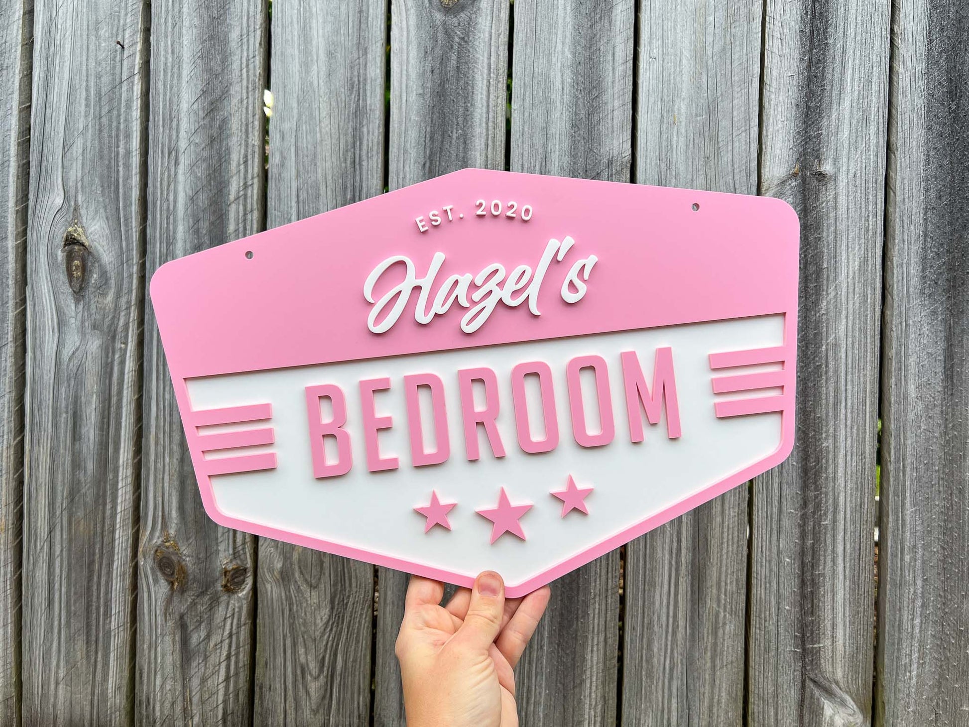 Beachy style retro badge size with 'Hazel's Bedroom' in frangipani pink and white.