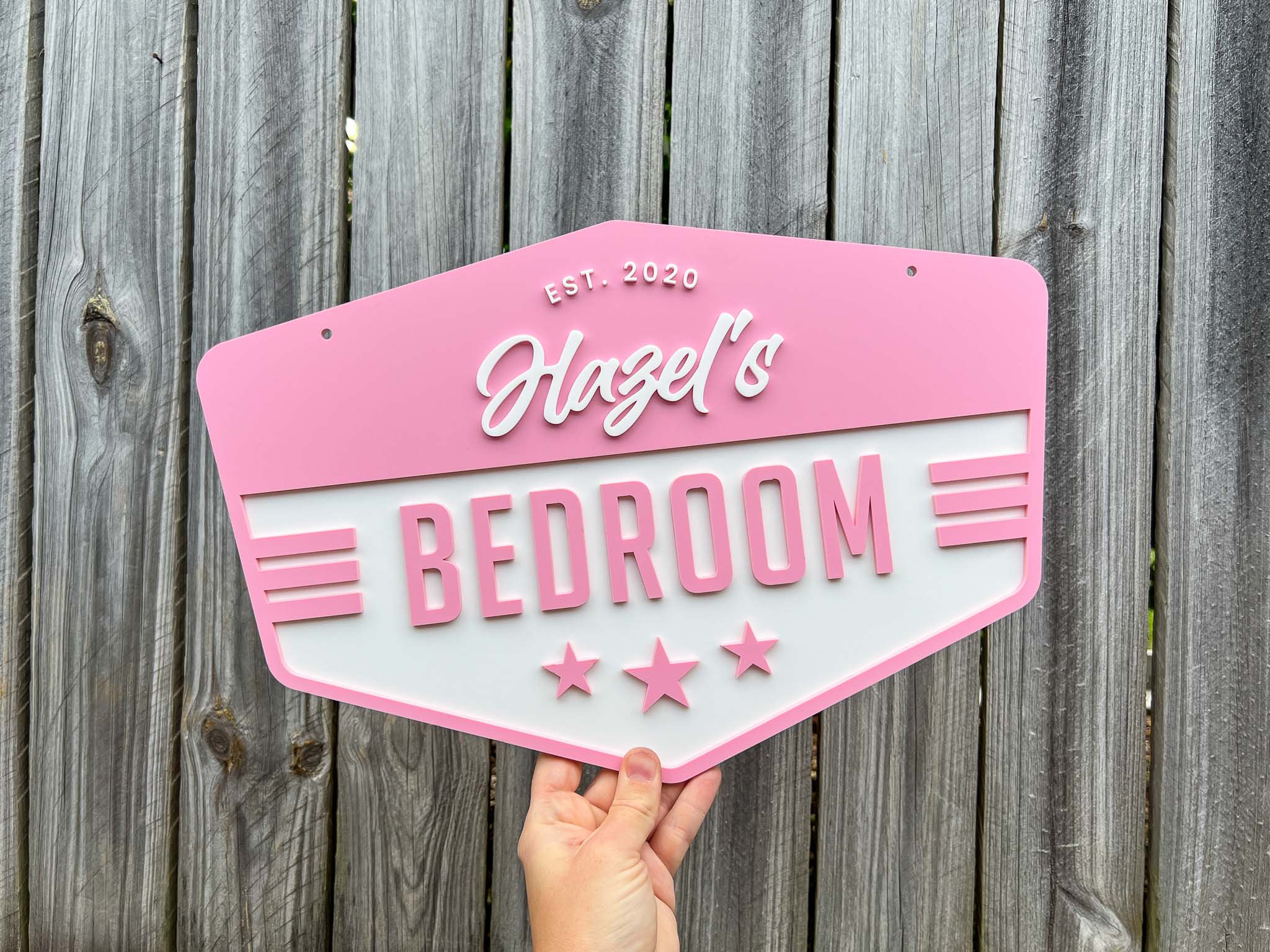 Beachy style retro badge size with 'Hazel's Bedroom' in frangipani pink and white.