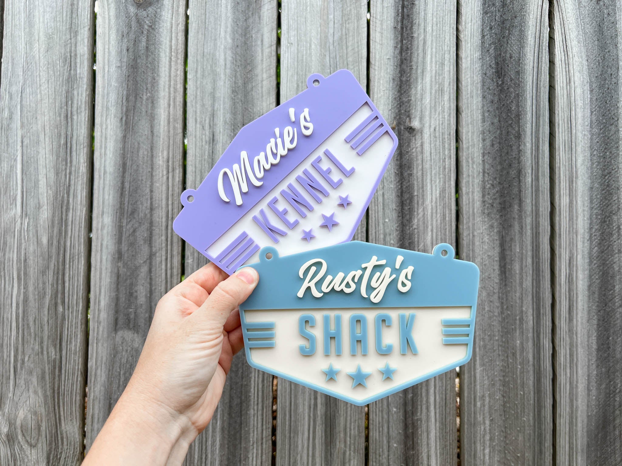 Two metal signs with text held against a wooden fence background | Coji Designs