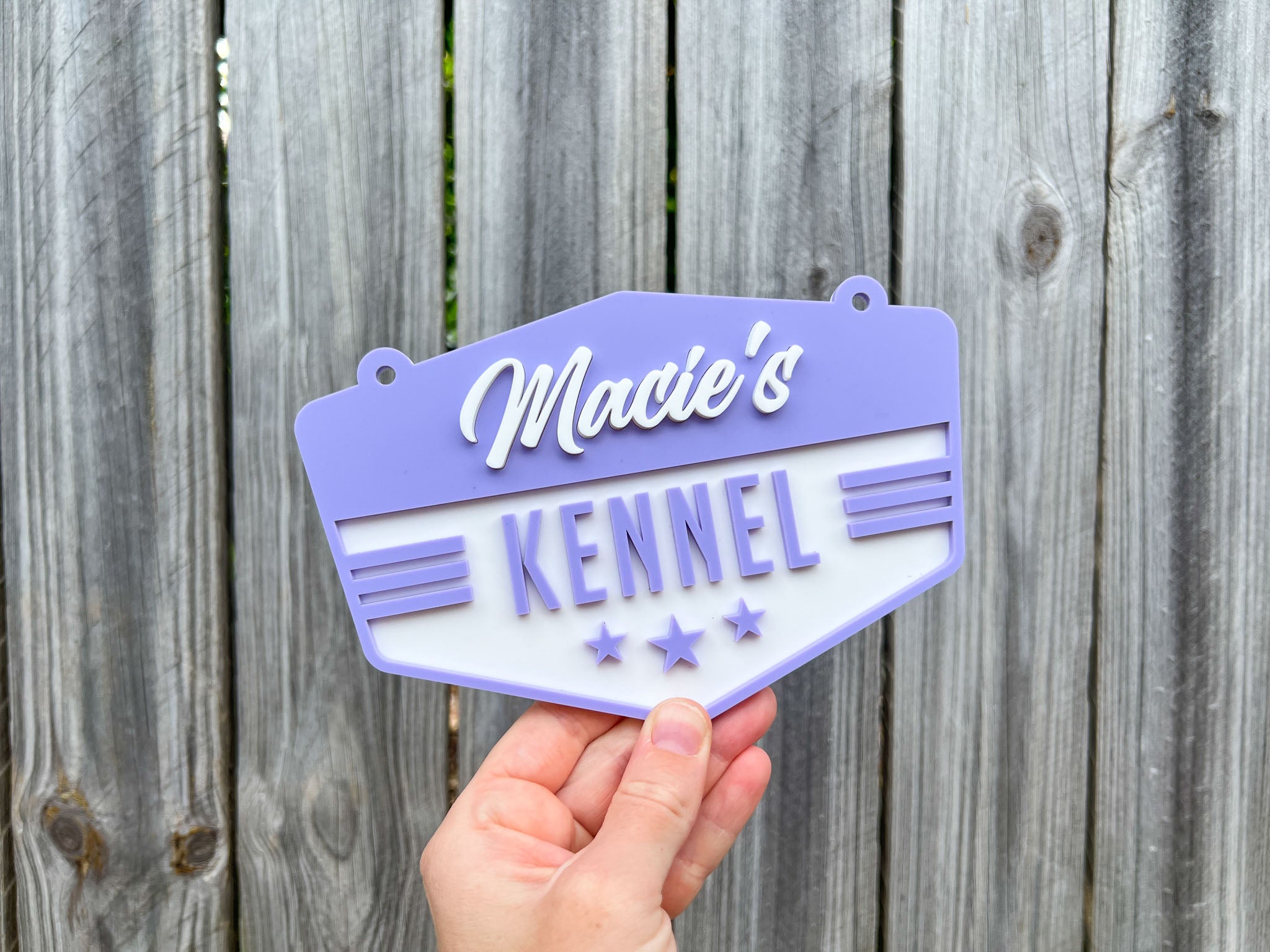 Hand holding a purple and white sign with 'Macie's Kennel' text against a wooden fence background | Coji Designs