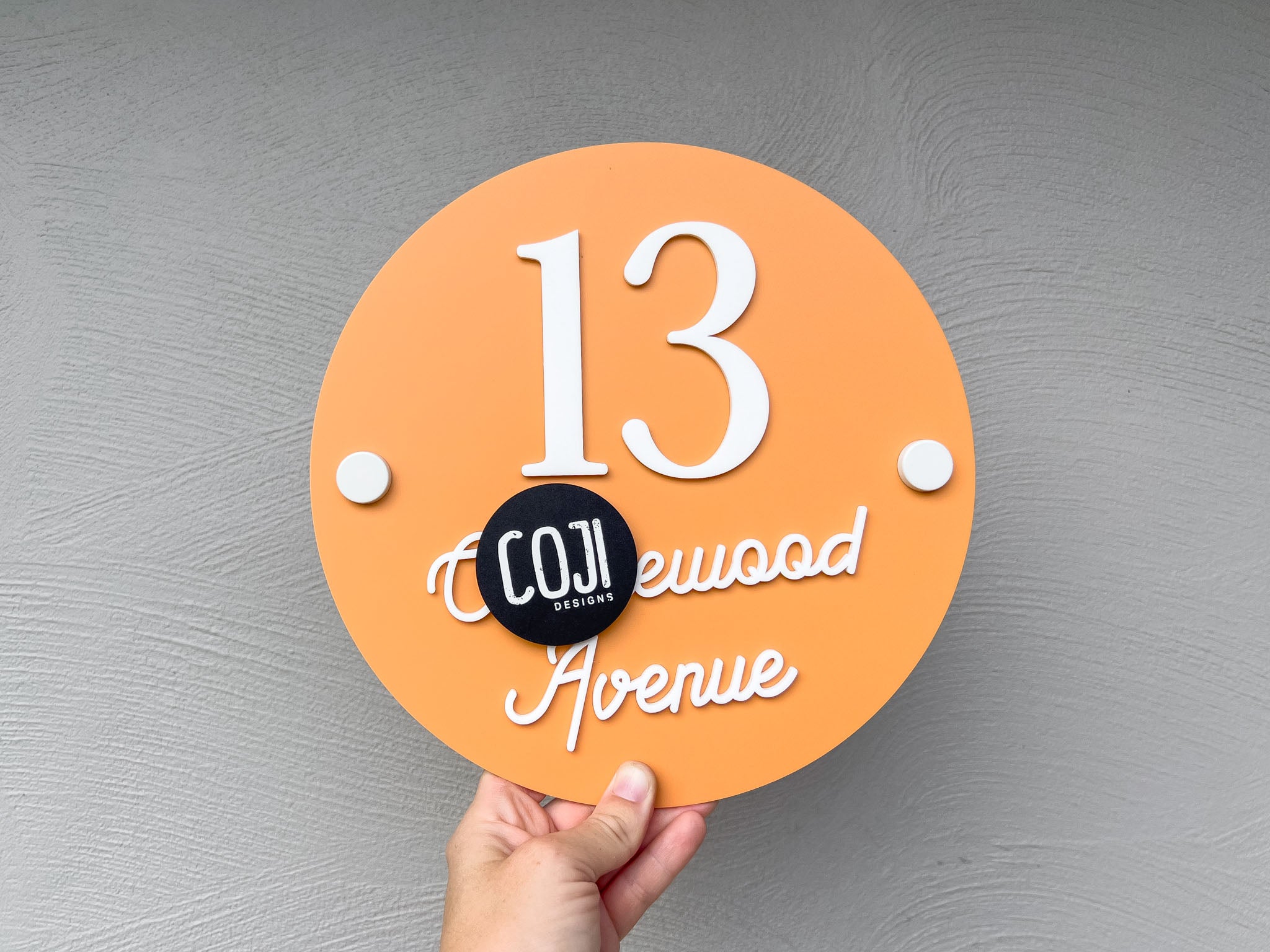 Tropical orange and white coastal style street adress round plaque with the number '13'.