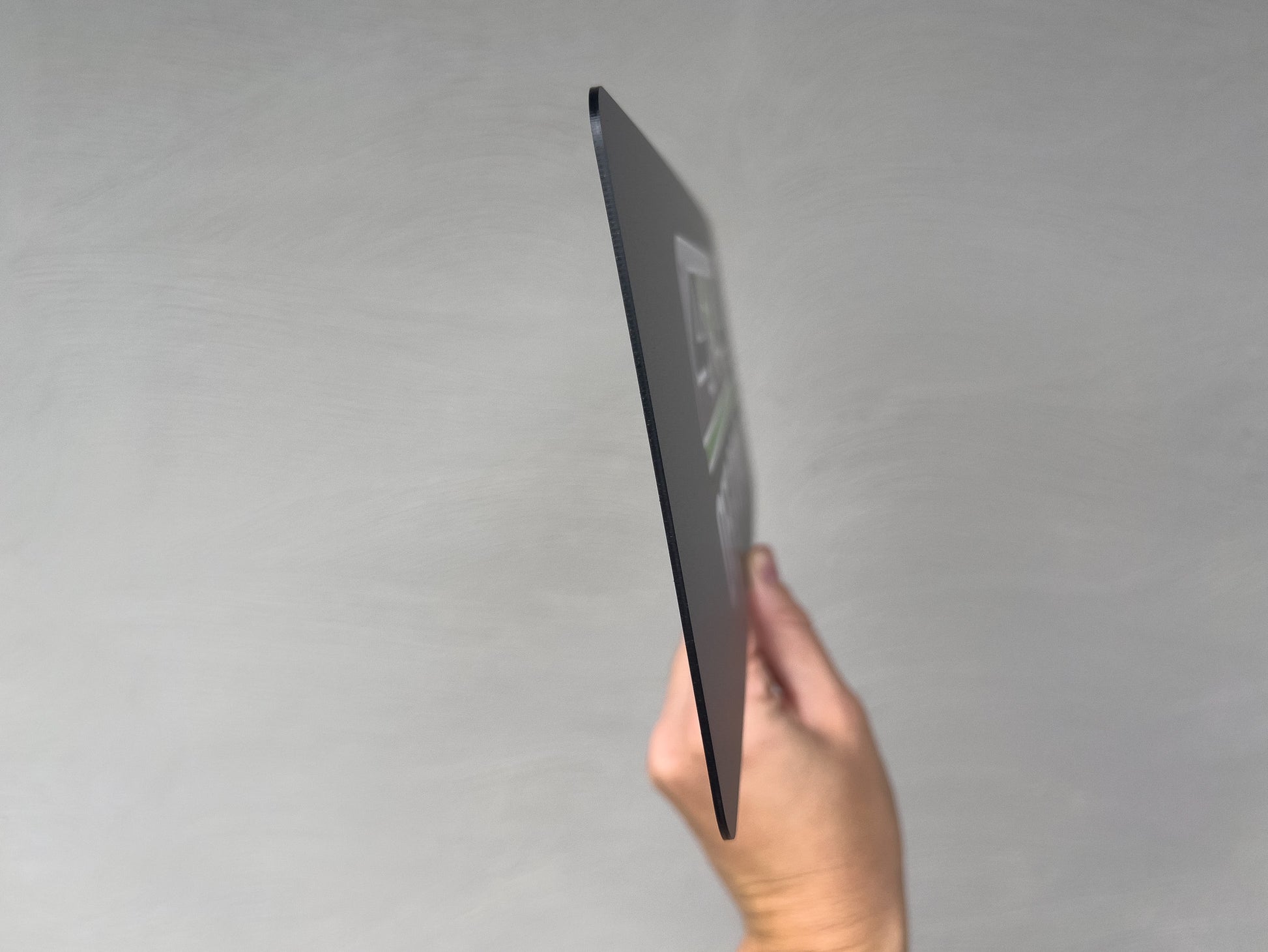 Hand holding a side view of the Denham flexi logo plates