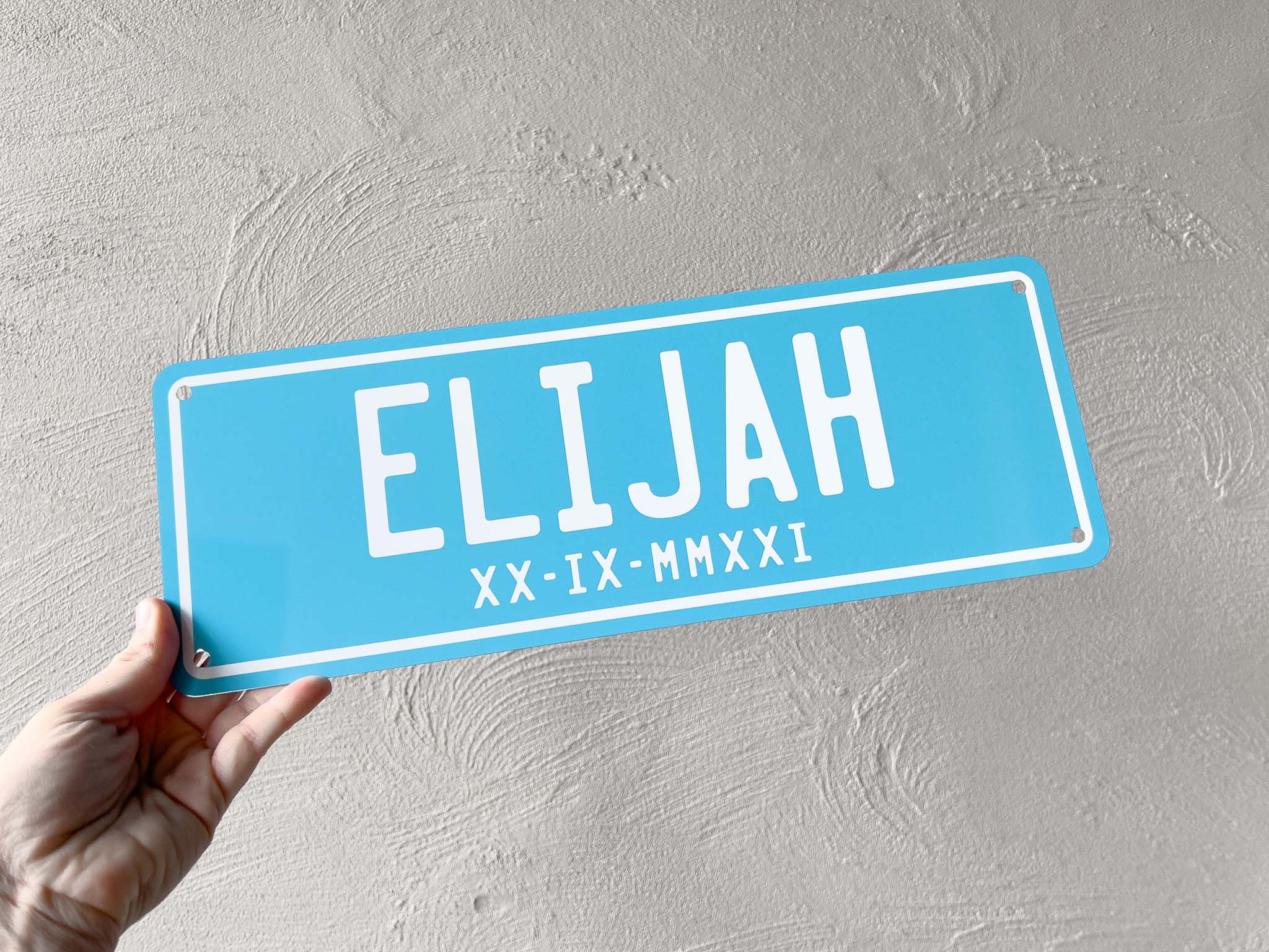 Light salt blue colour custom printed number plate sign that says 'ELIJAH' with a roman numerals date.