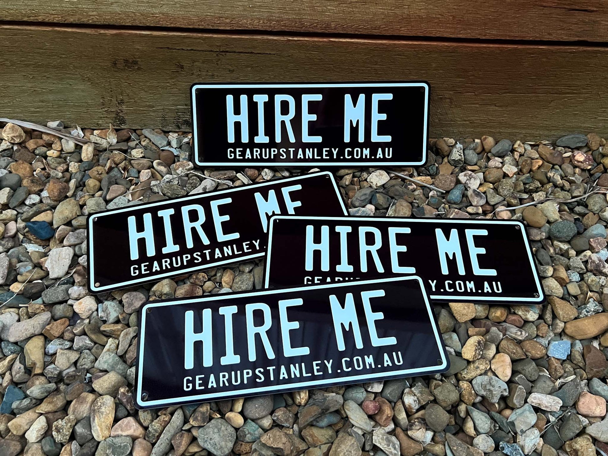 Black and white custom printer number plate style signs that say 'HIRE ME'.