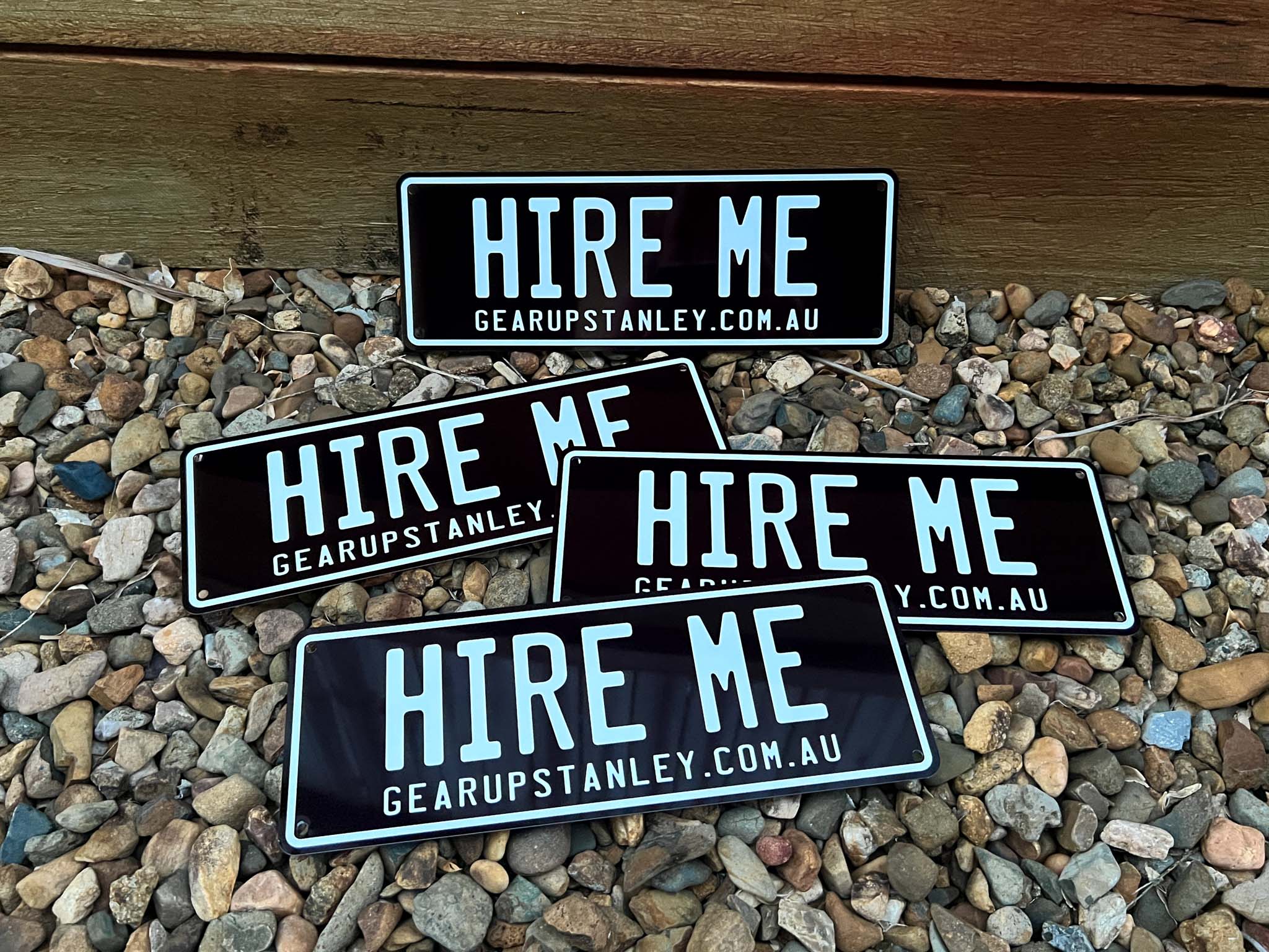 Black and white custom printer number plate style signs that say 'HIRE ME'.