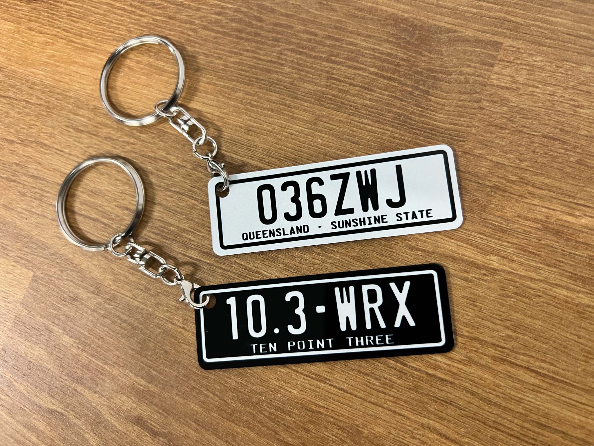 Two license plate style metal keychains in black and white.