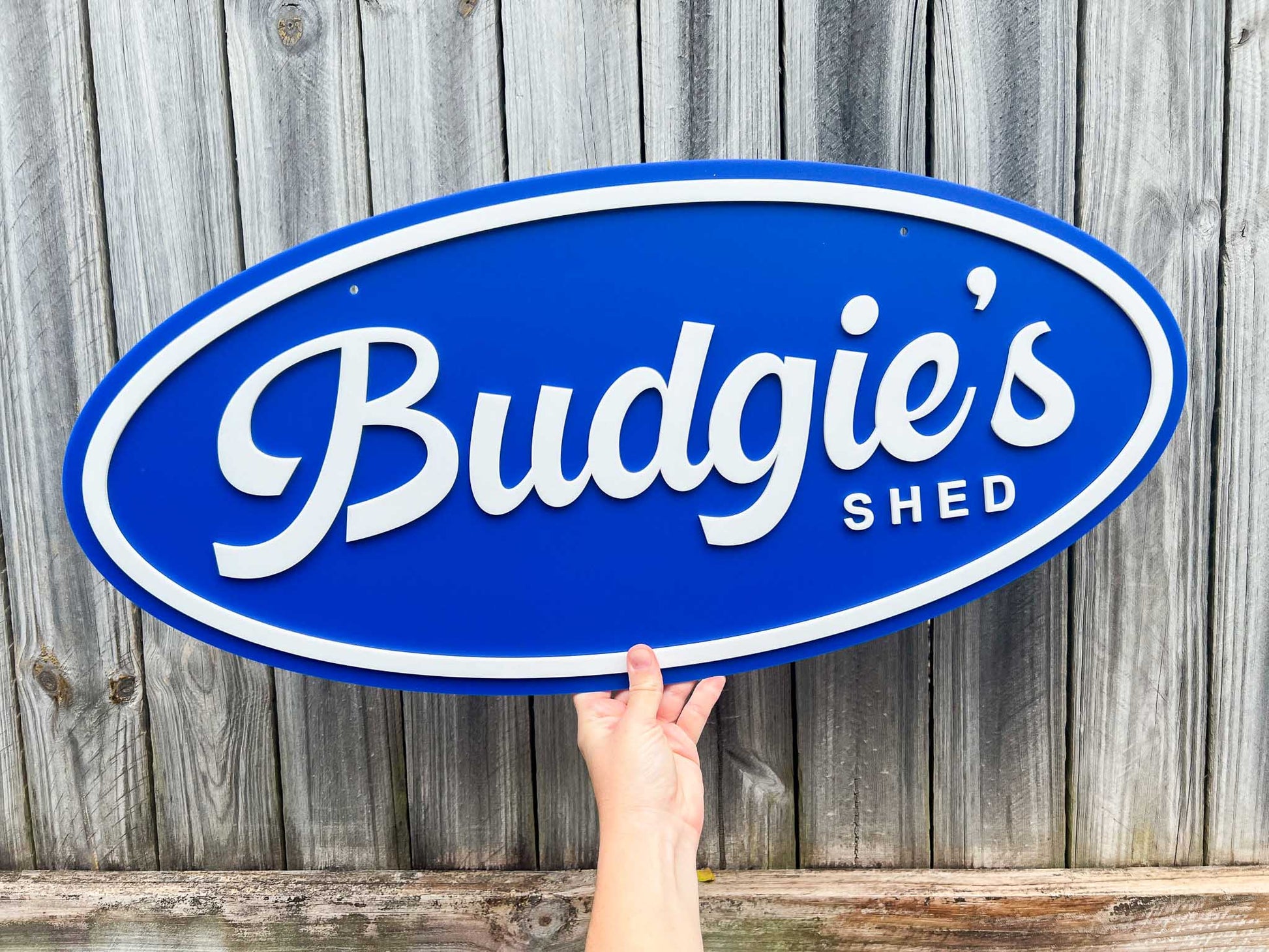 Personalised retro oval sign that says 'Budgie's Shed' in a coastal blue and white colour.