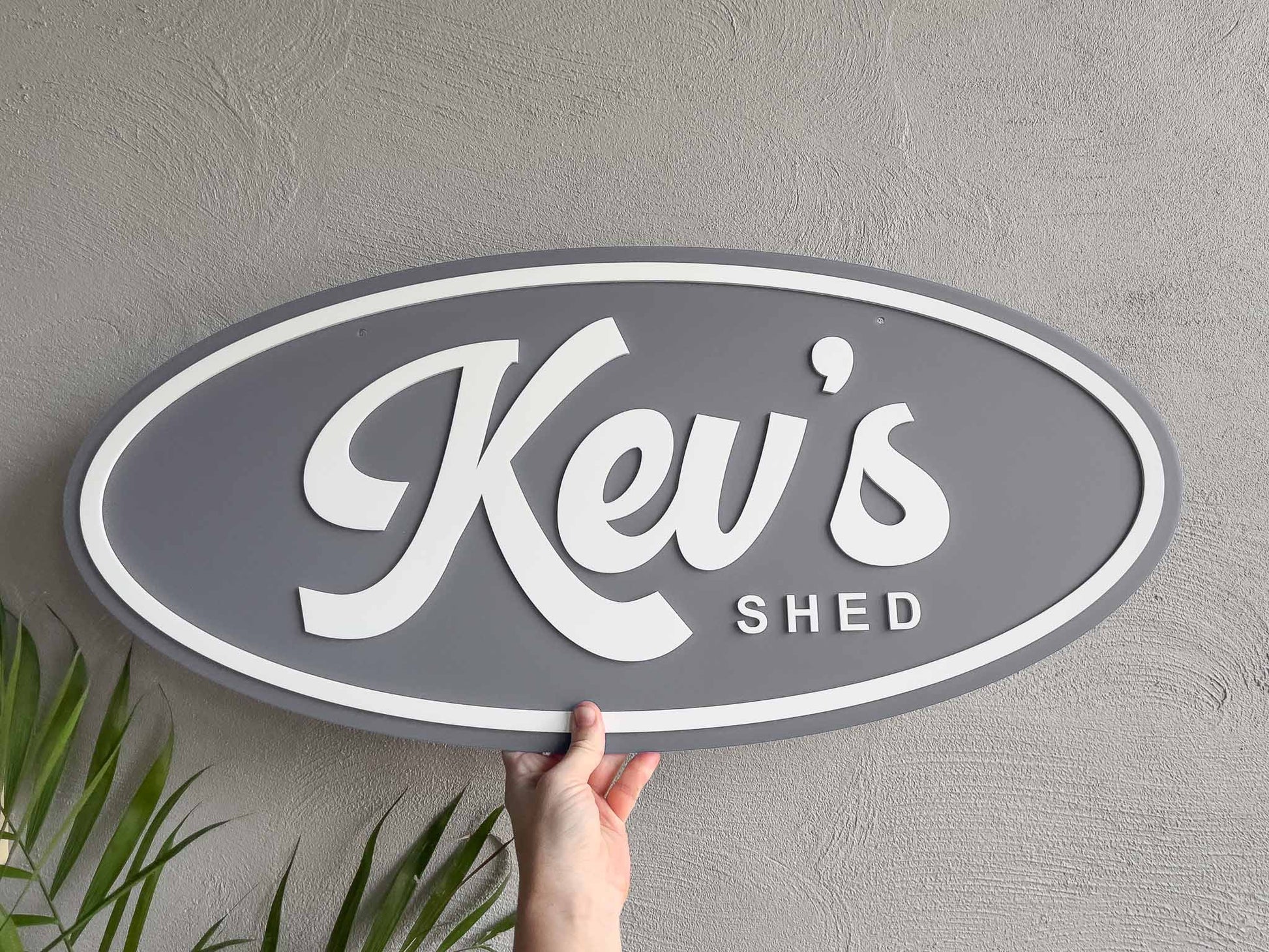Oval custom made 3D acrylic sign with 'Kev's Shed' in grey and white.