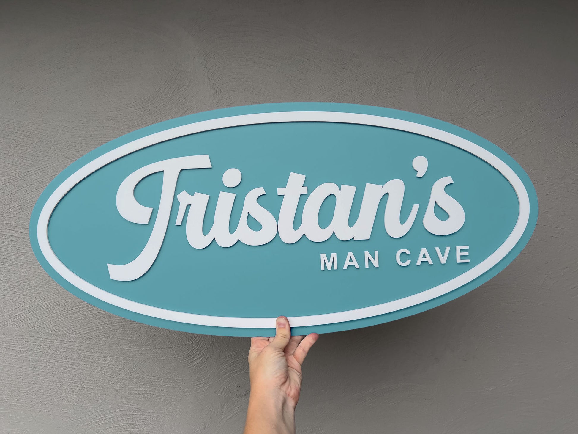 Retro mechanic's badge inspired custom wall art that says 'Tristan's Man Cave' in a seafoam coastal blue colour.