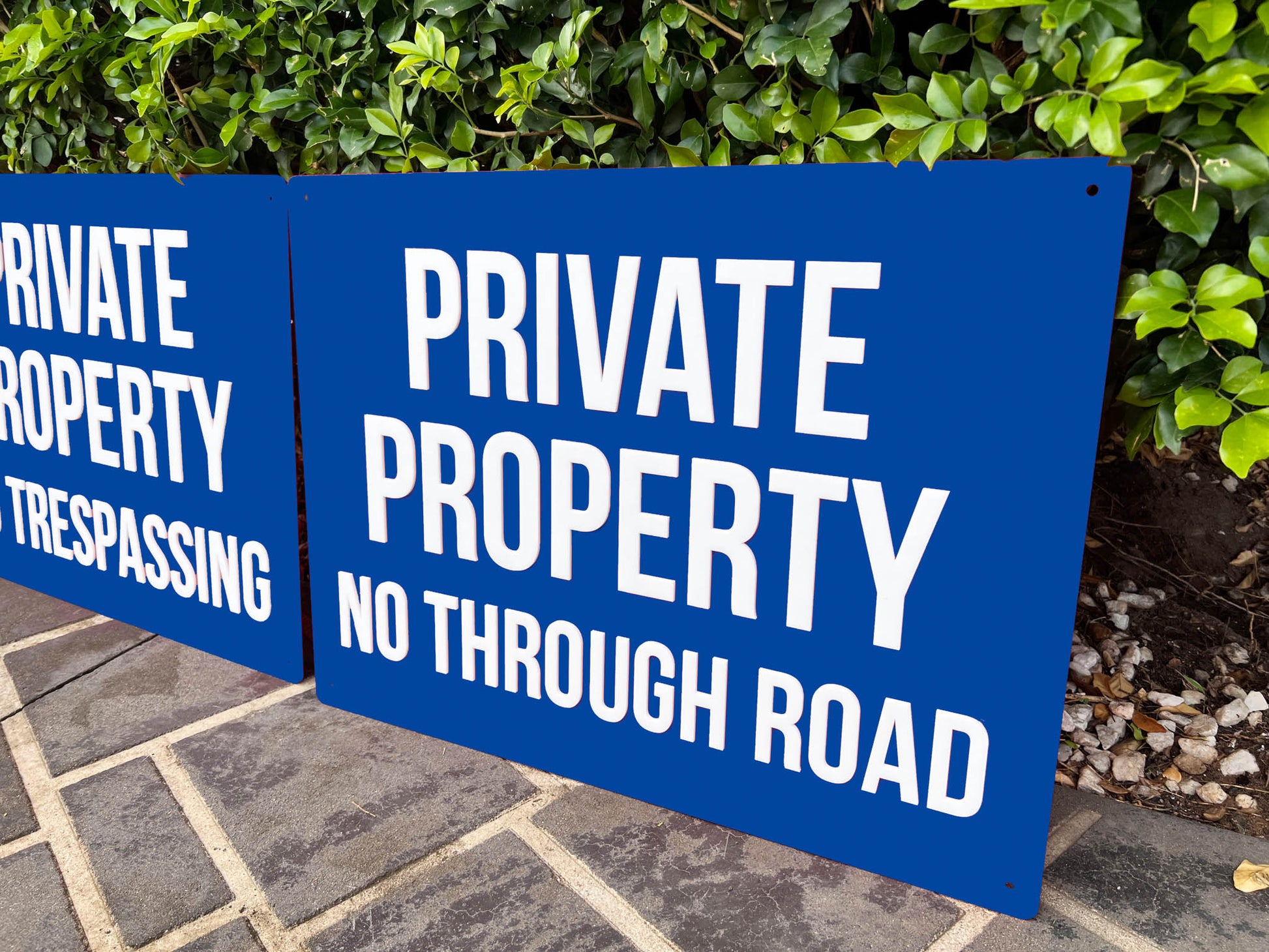 Two blue custom signs with white text warning about private property and trespassing.