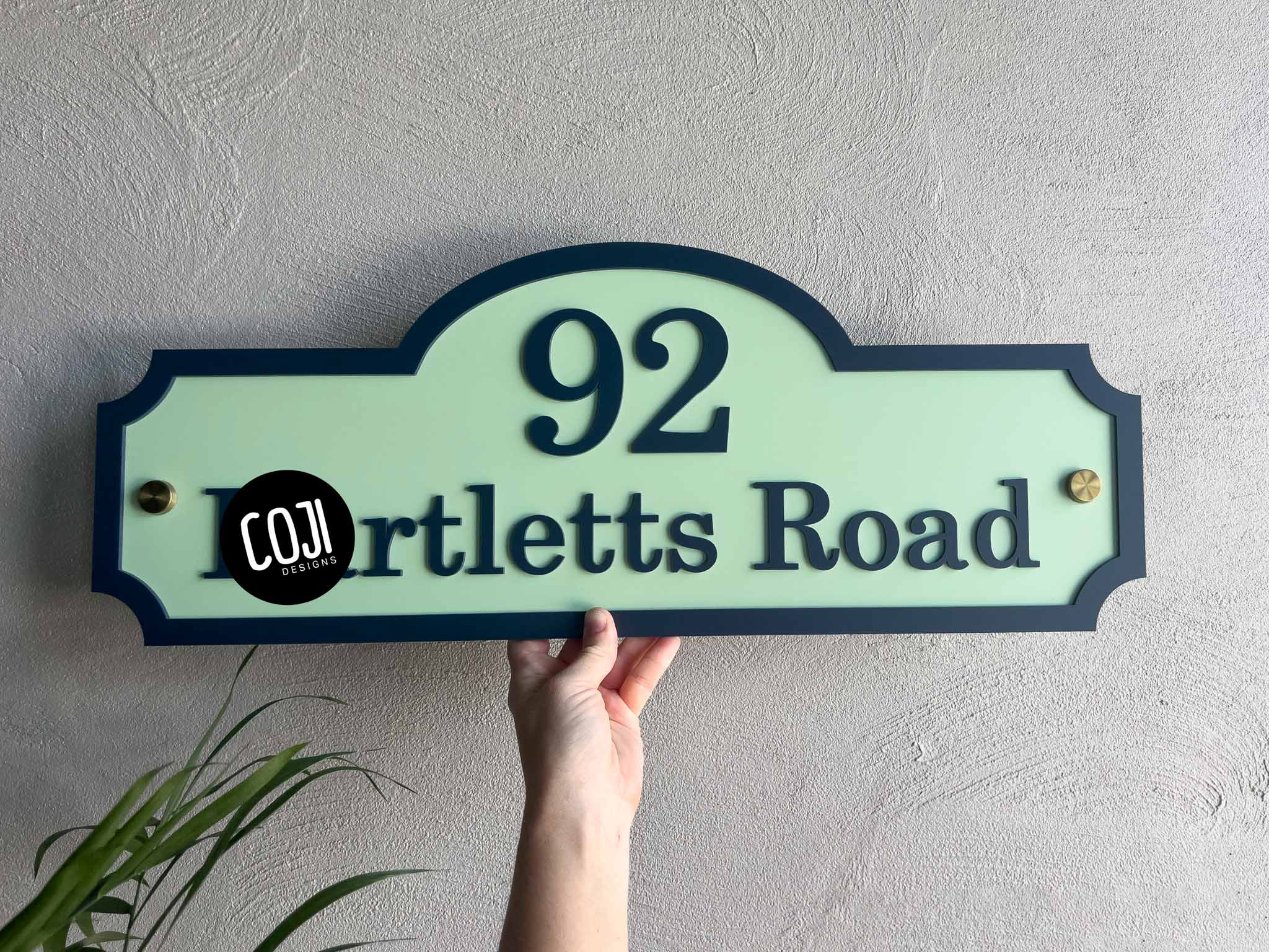 Hand holding a green and deep blue sign with the number '92 on it.