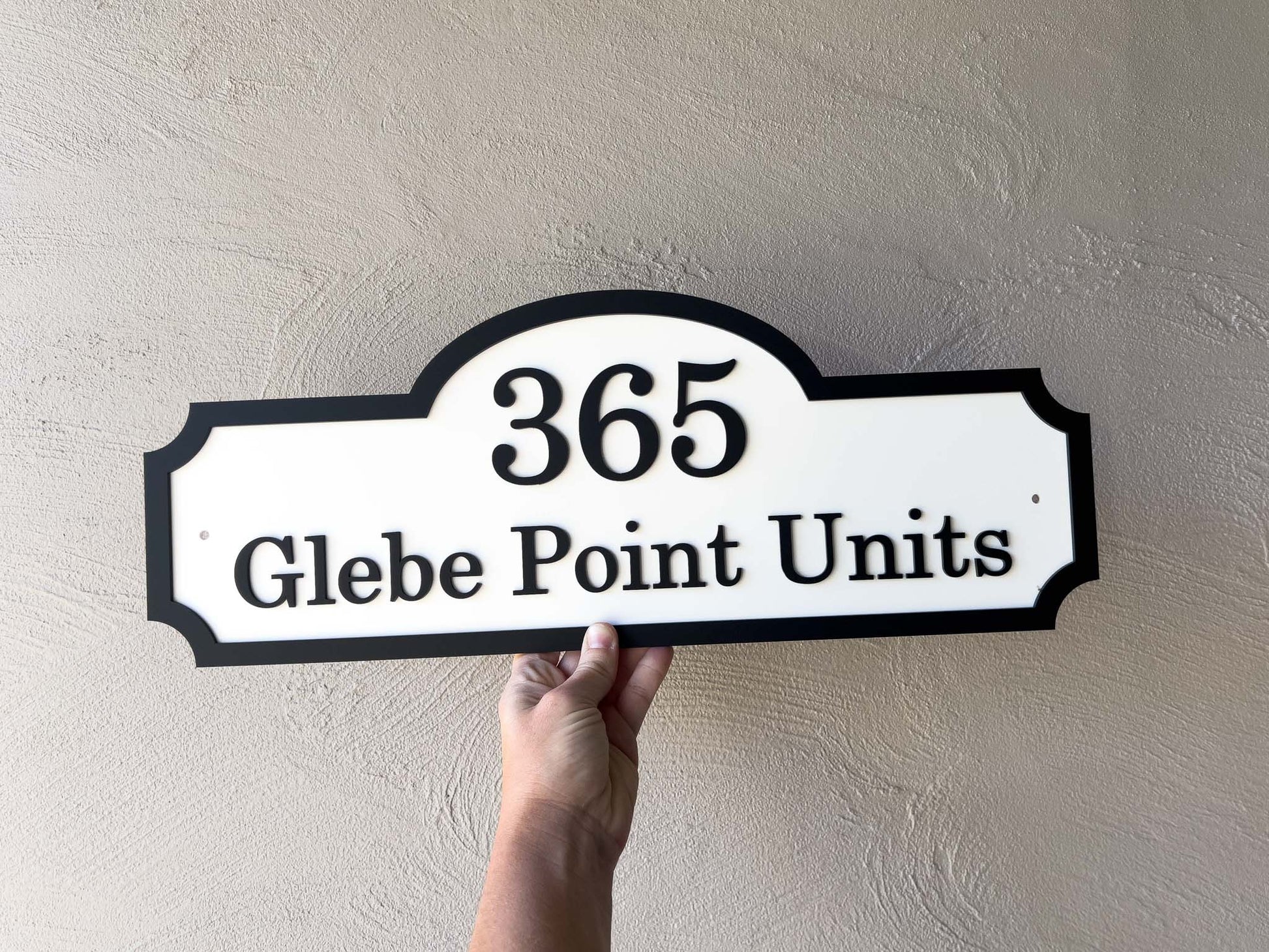 Hand holding a custom hampton style sign with '365 Glebe Point Units' against a beige wall.