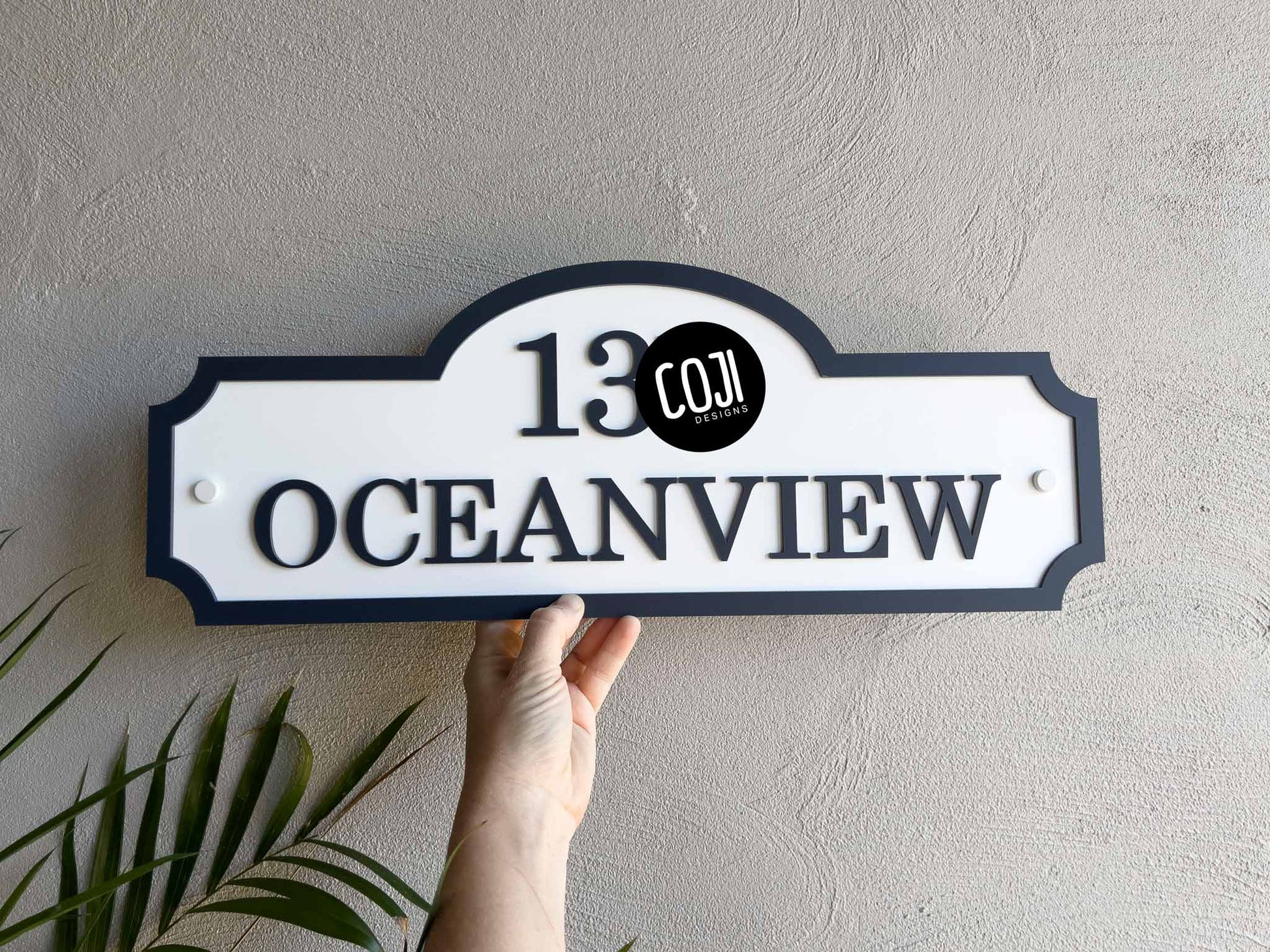 A tropical vintage white and deep blue house sign with the word 'Oceanview' written on it.