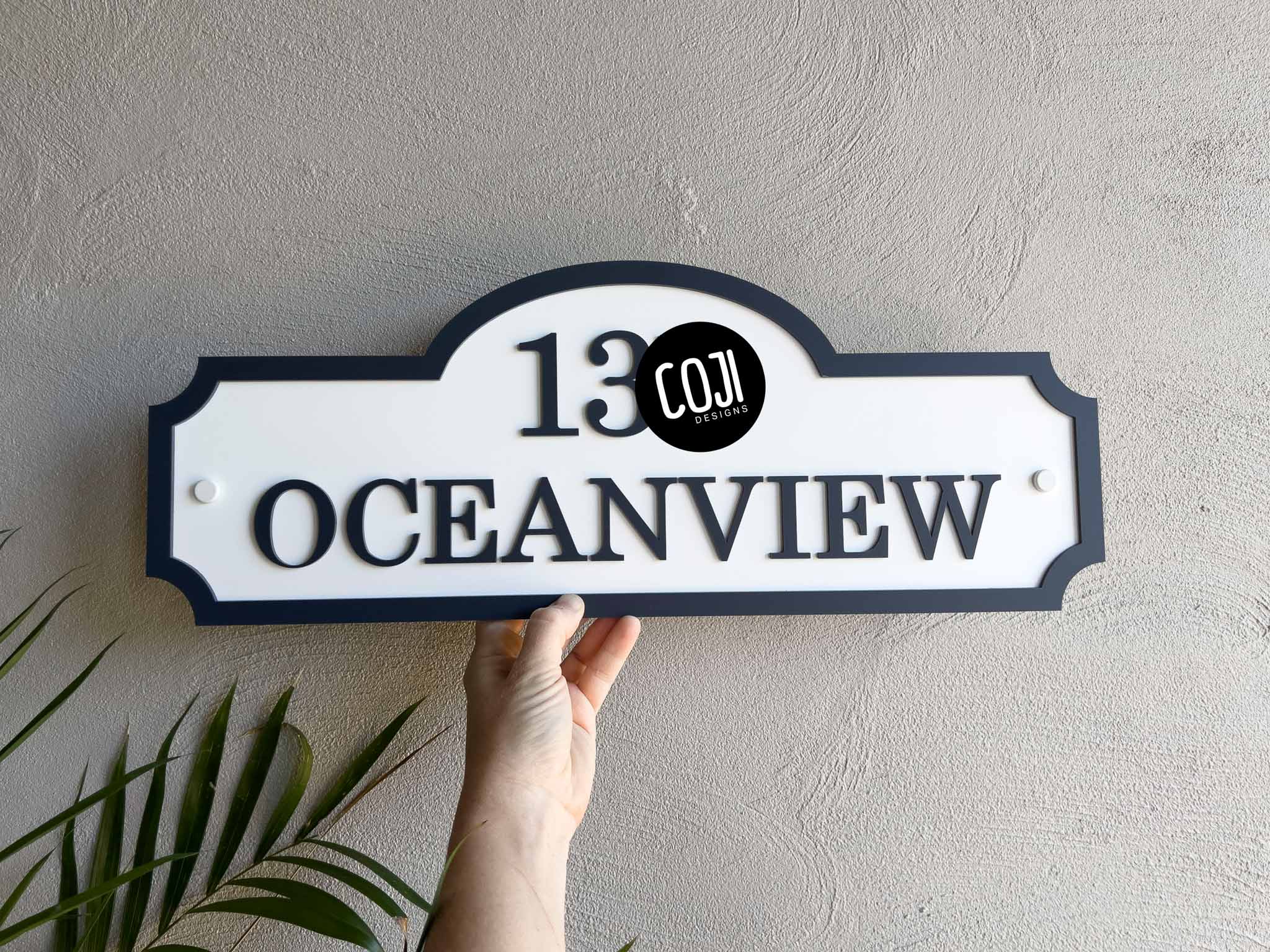 A tropical vintage white and deep blue house sign with the word 'Oceanview' written on it.