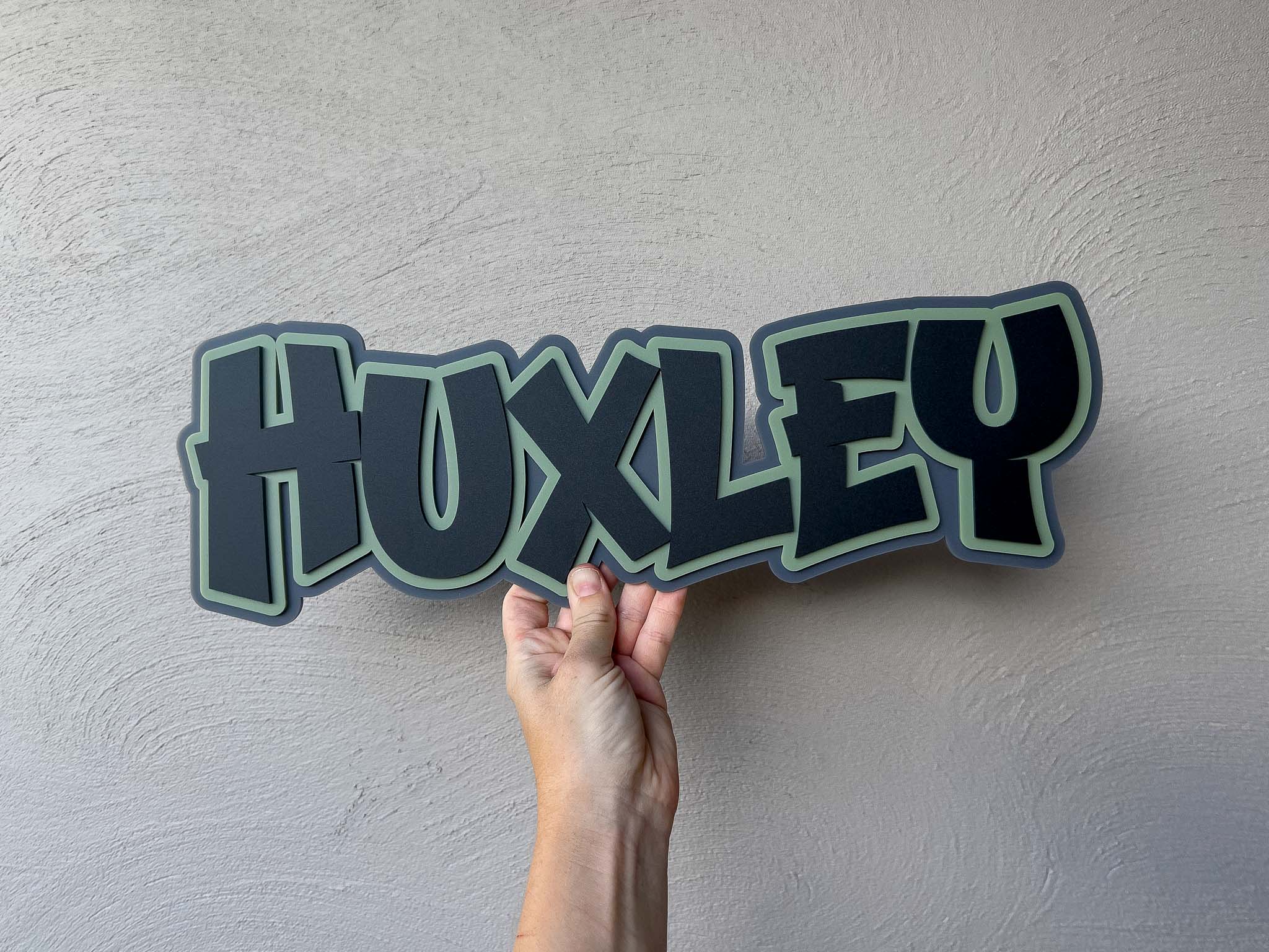 Cool retro name plaque in a graffiti style font that says 'Huxley'.