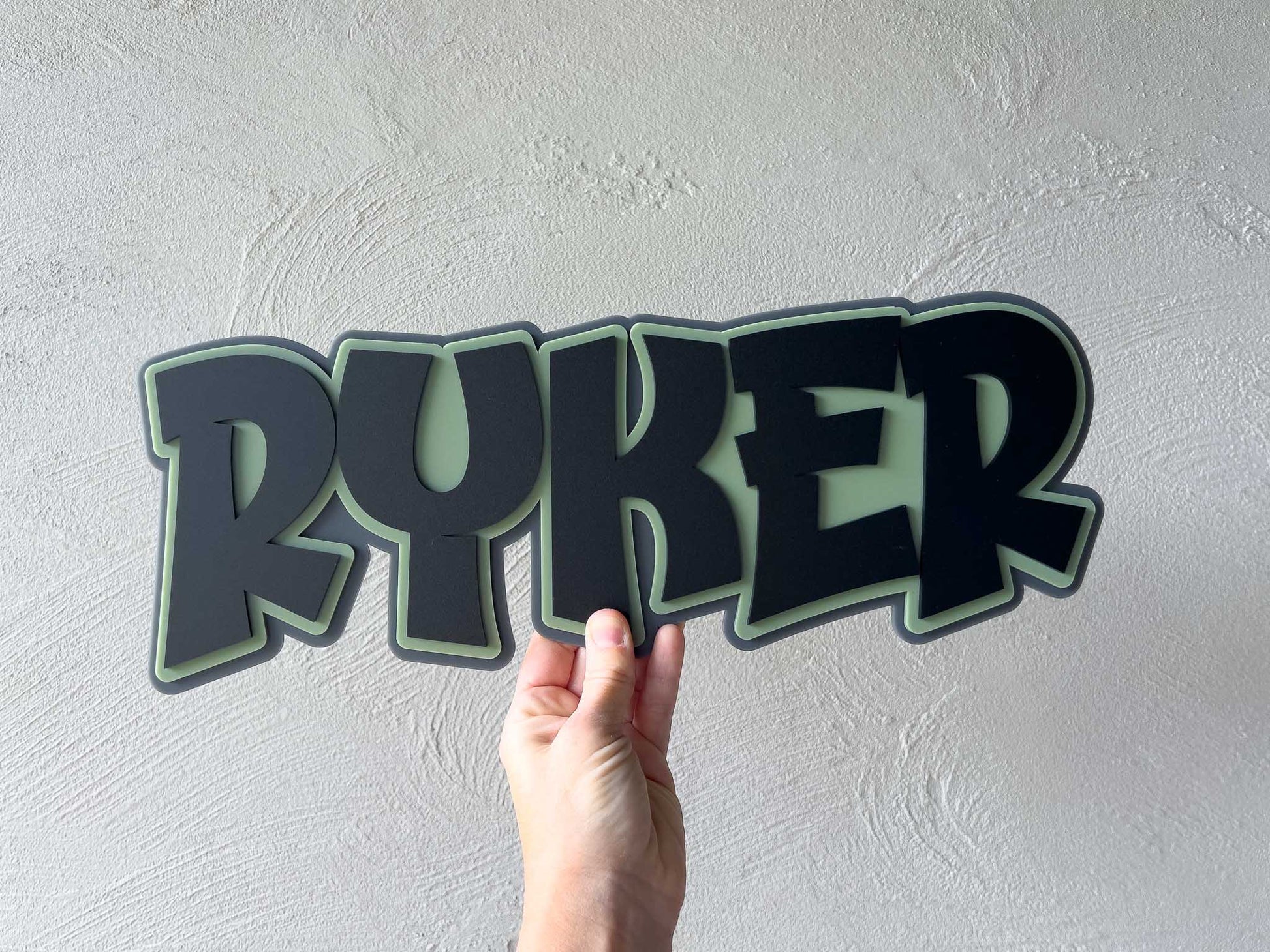 Personalised funky bold retro name sign in army green, black and dark grey that reads 'Ryker'