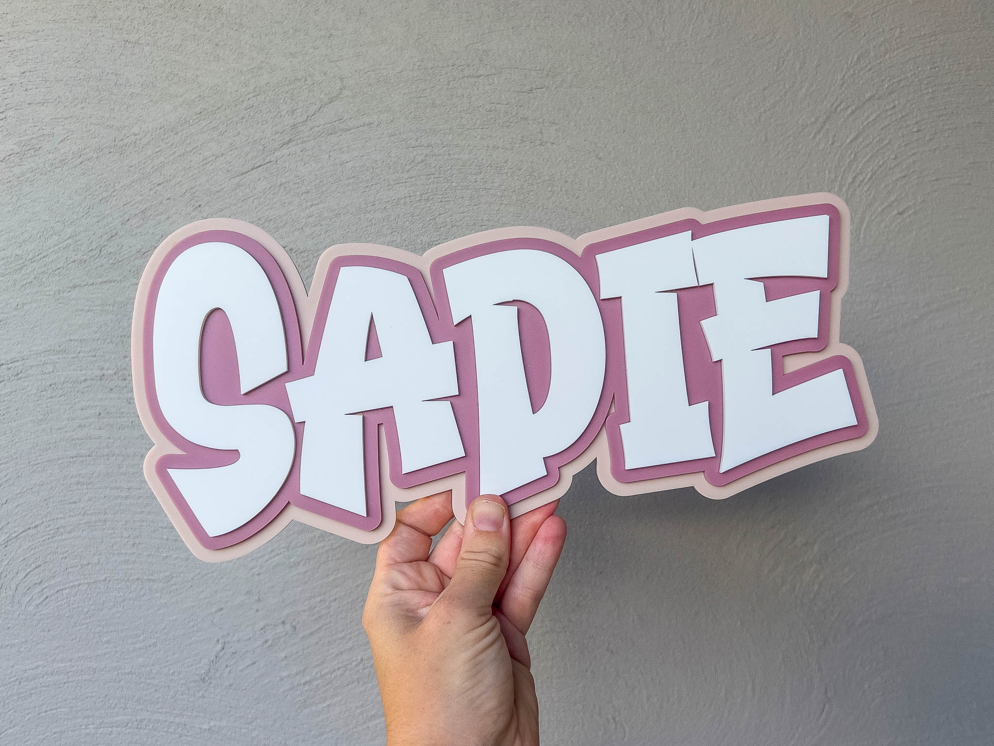 Funky retro name plaque in dusty rose, beige and white with the name 'SADIE'.