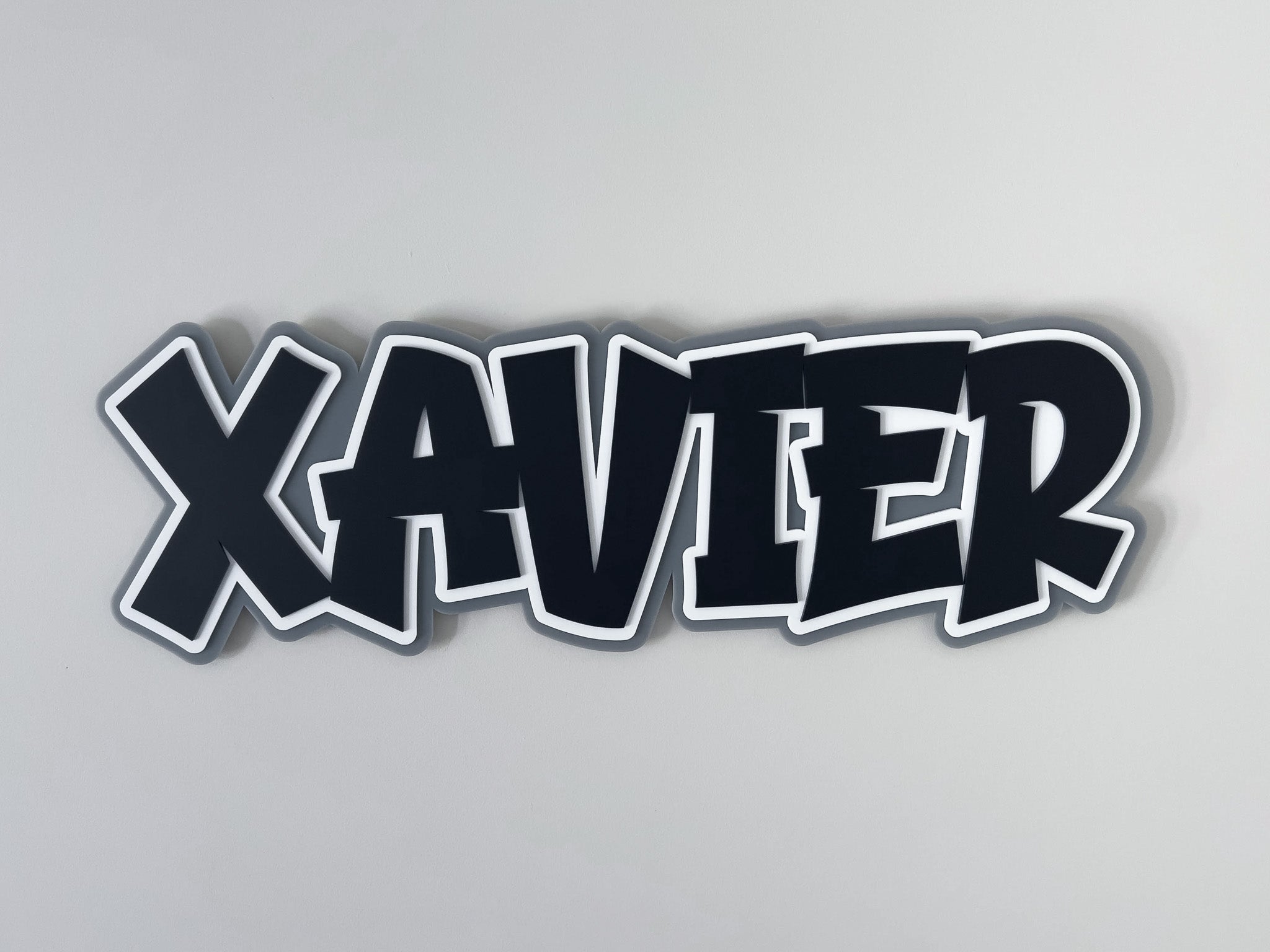 Custom retro graffiti style 3D name plaque with the name 'XAVIER' laser cut in black, white and grey.