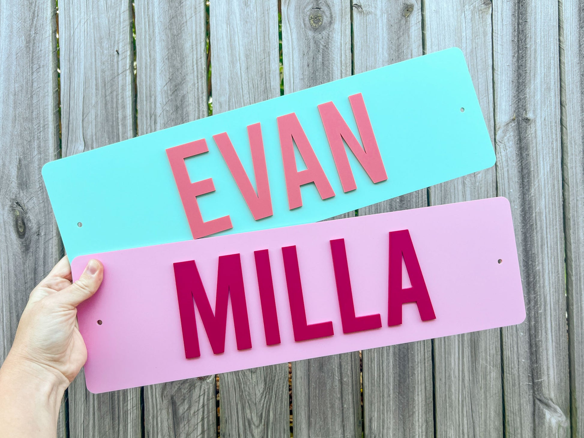 Two custom 3D acrylic name plates with laser cut acrylic lettering in green and pink that say 'EVAN' & 'MILLA'.
