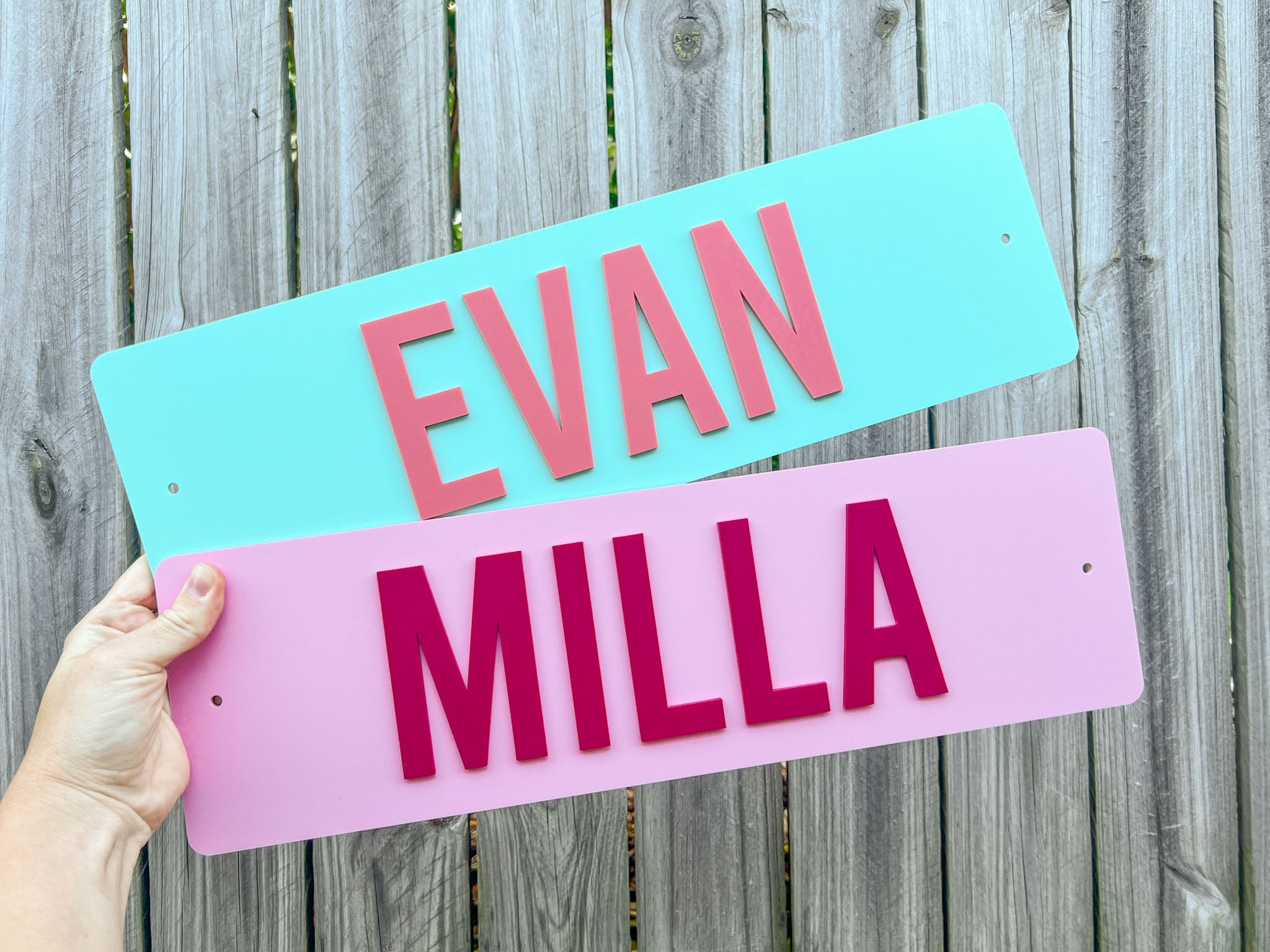 Two custom 3D acrylic name plates with laser cut acrylic lettering in green and pink that say 'EVAN' & 'MILLA'.