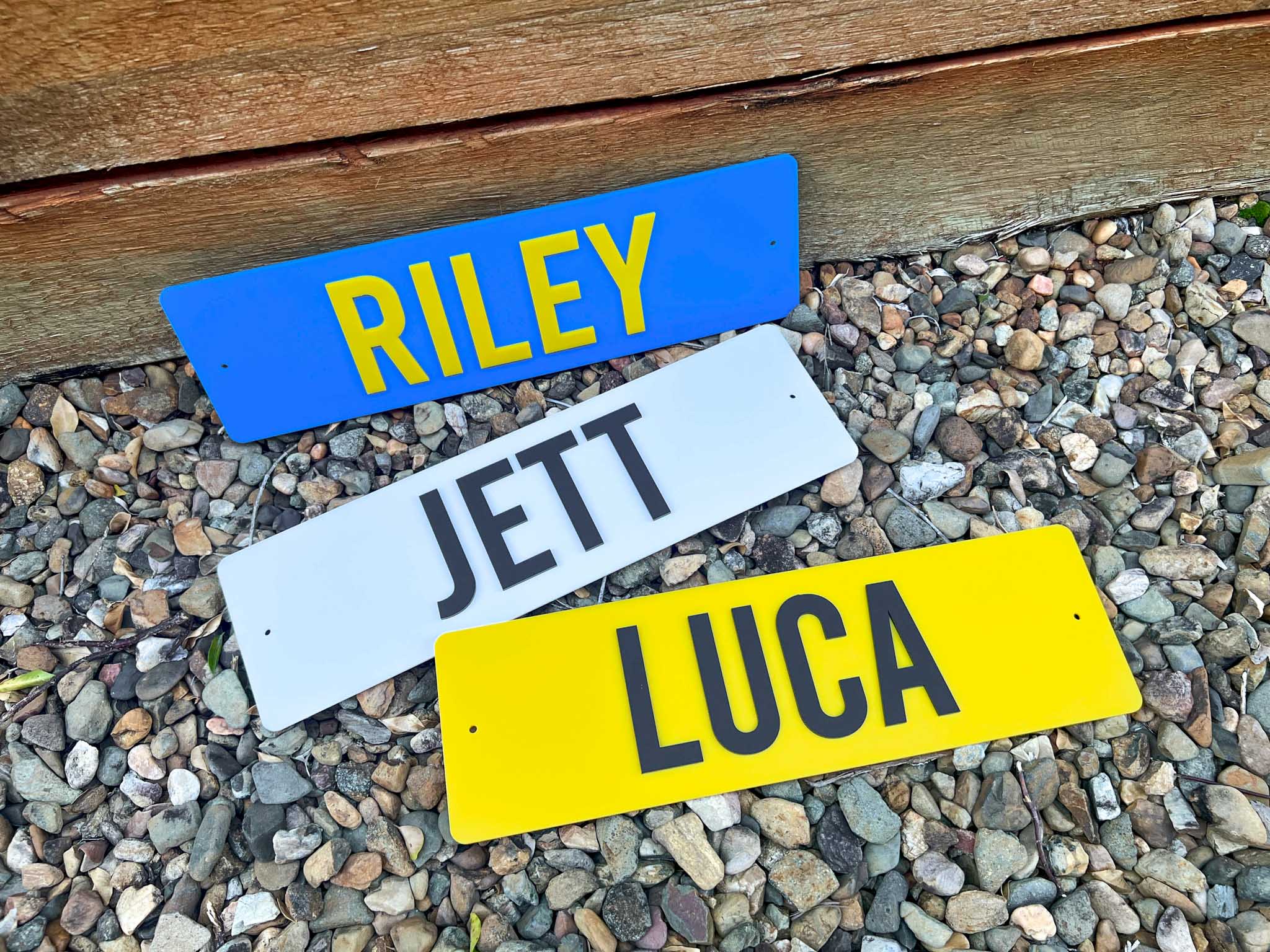 Three nameplates labeled 'RILEY', 'JETT', and 'LUCA' on a pebble surface.