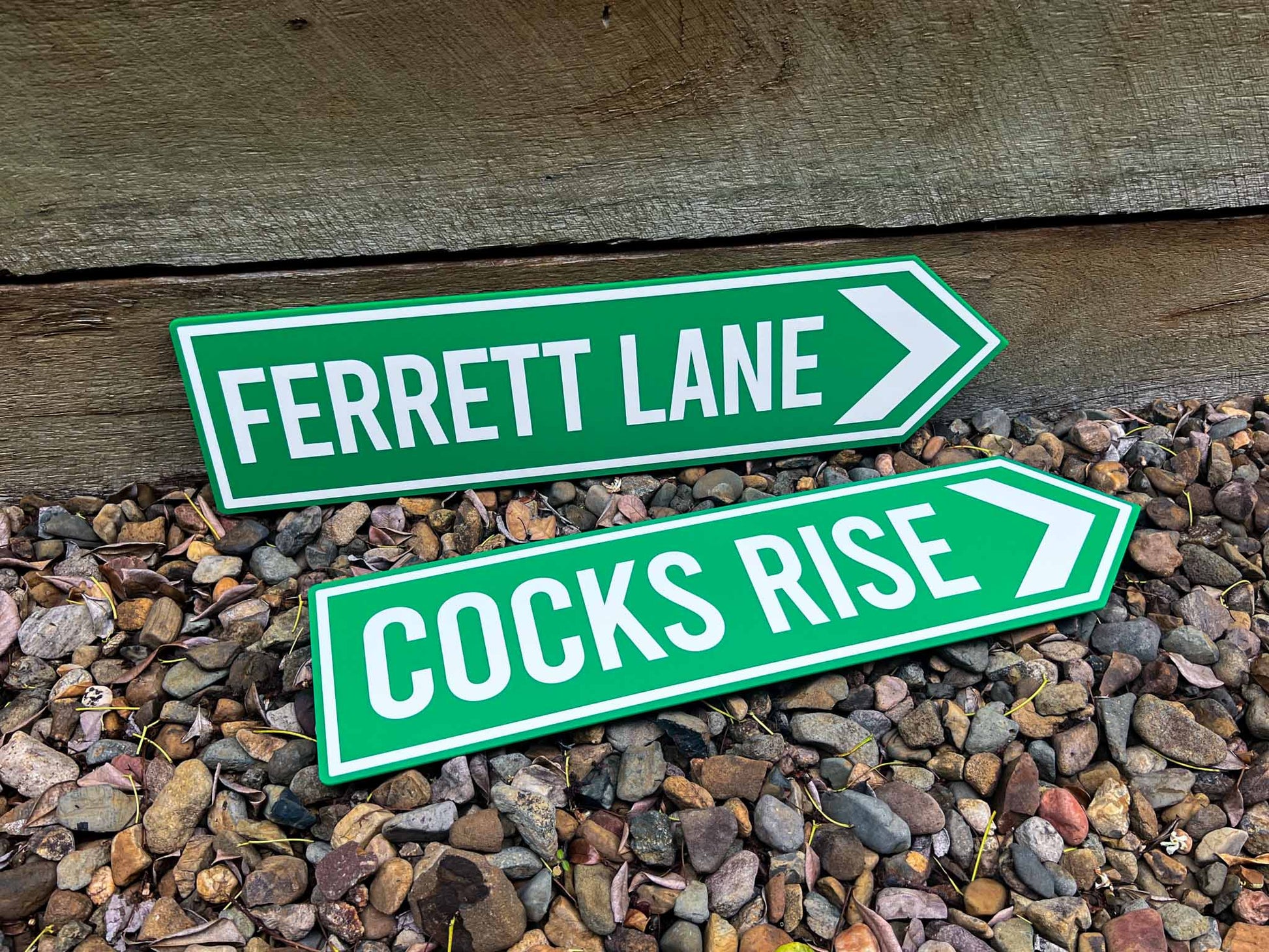 Classic pointer sign in green and white that read 'COCKS RISE' & 'FERRETT LANE'.