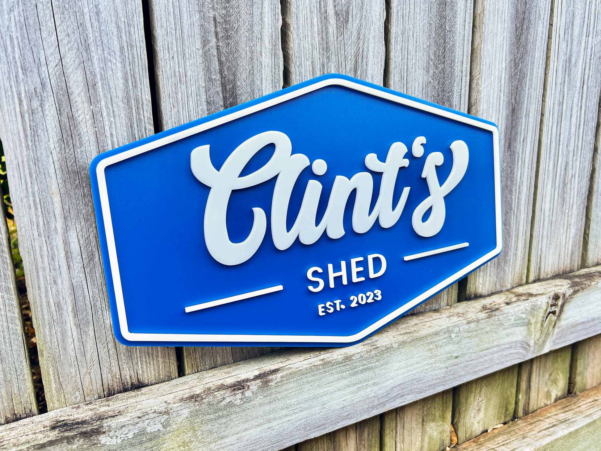 Retro vintage sign with 'Clint's Shed EST. 2023' on a wooden background