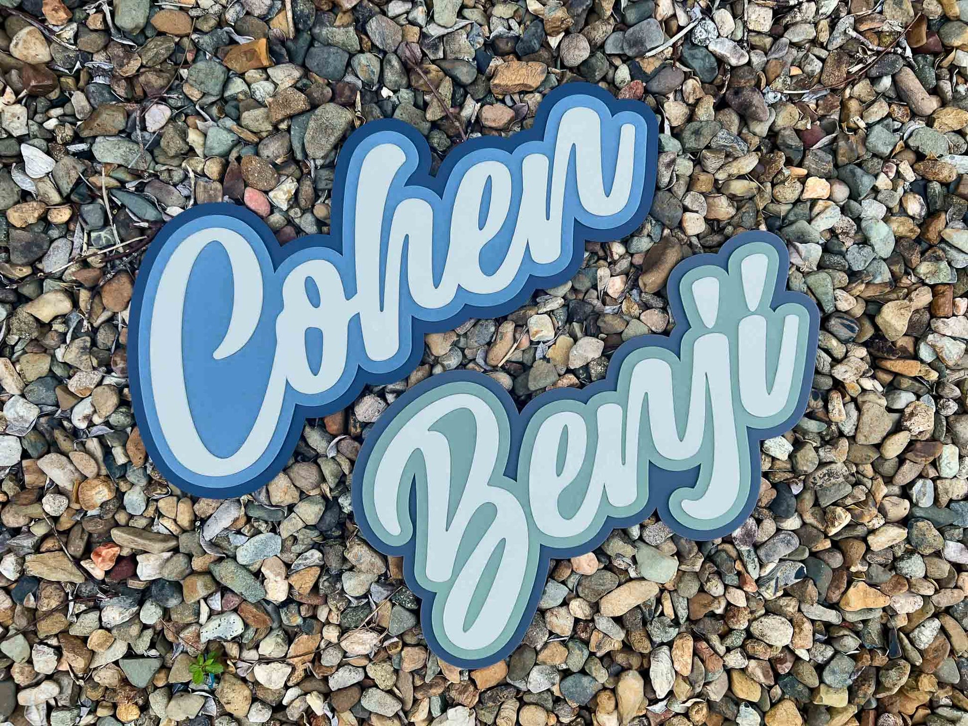 Two name patches, 'Cohen' and 'Benji', on a pebbled surface.
