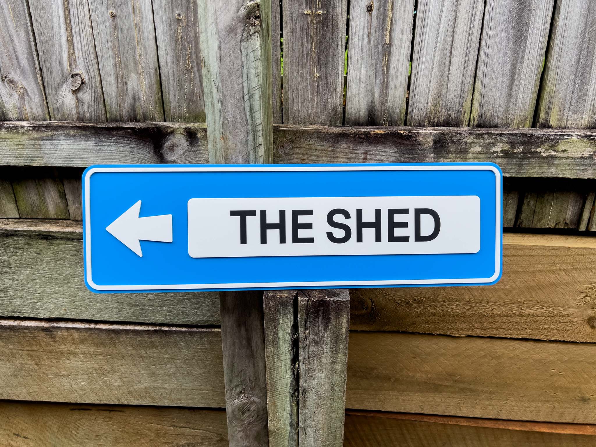 3D acrylic street sign that reads 'THE SHED' in blue and white.