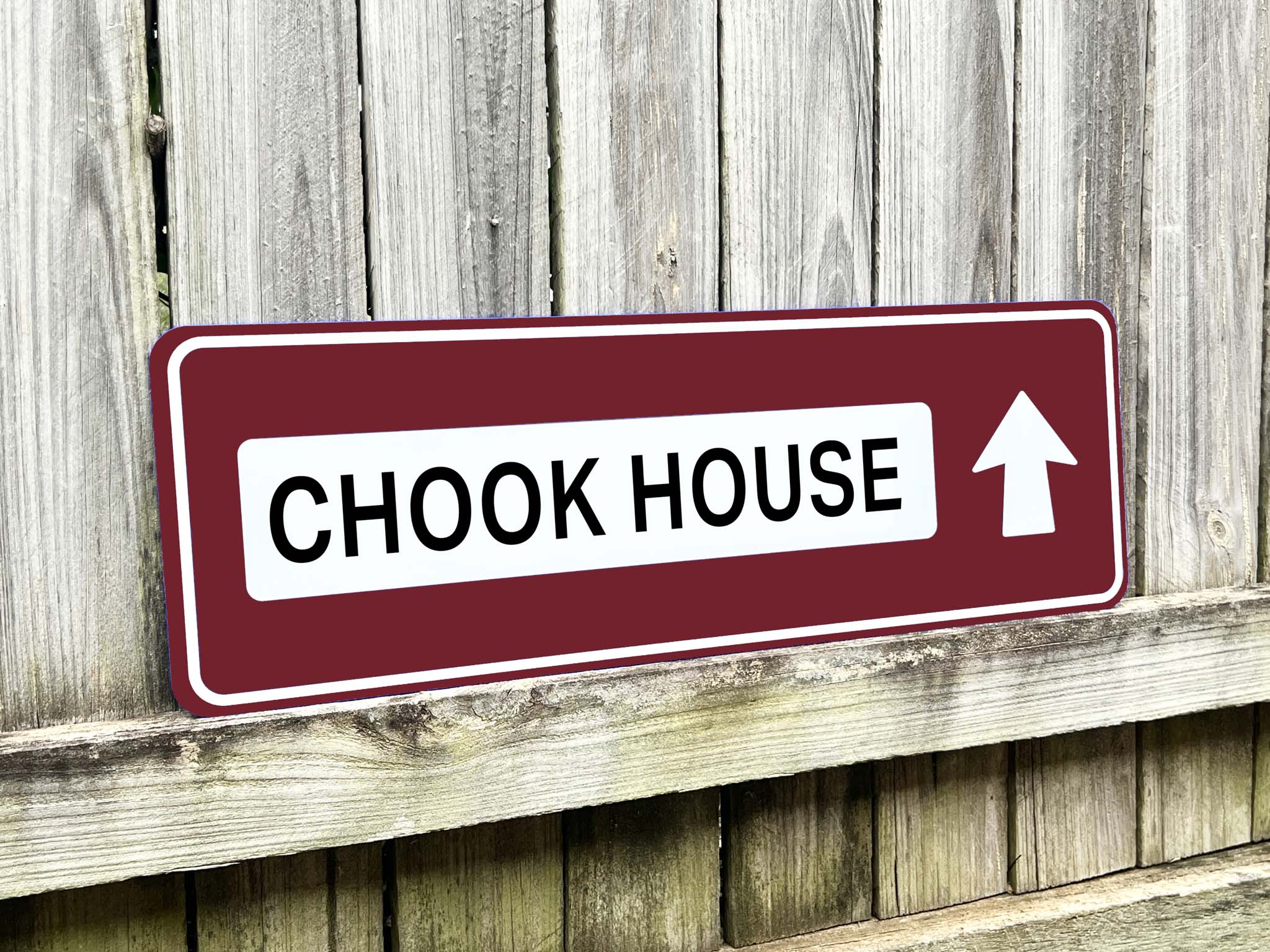 Sign pointing to 'Chook House' with an arrow on a wooden background