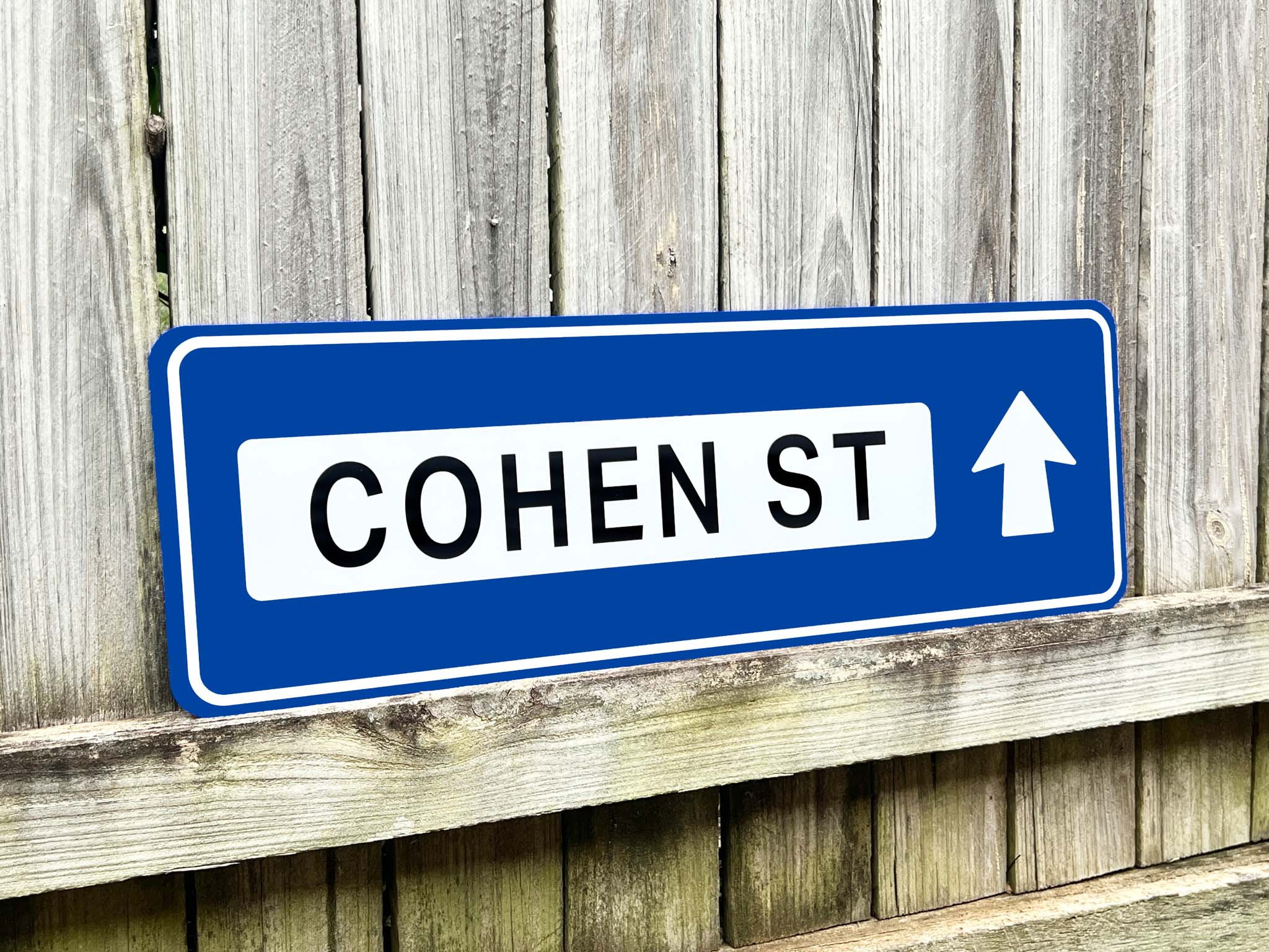 Street sign for Cohen St with an arrow on a wooden background