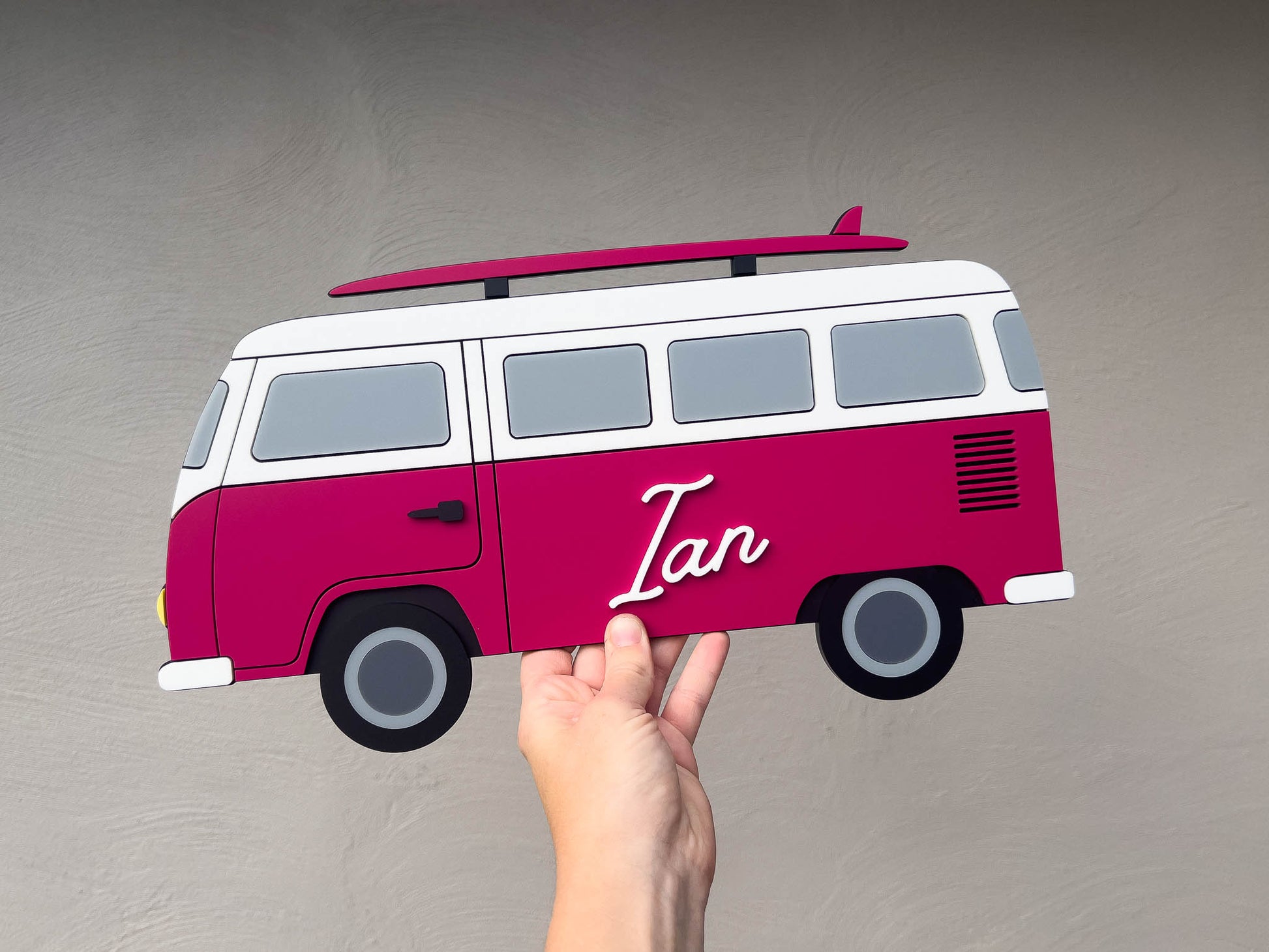 A custom made surf van shaped sign in a mulberry maroon colour that says 'Ian'.