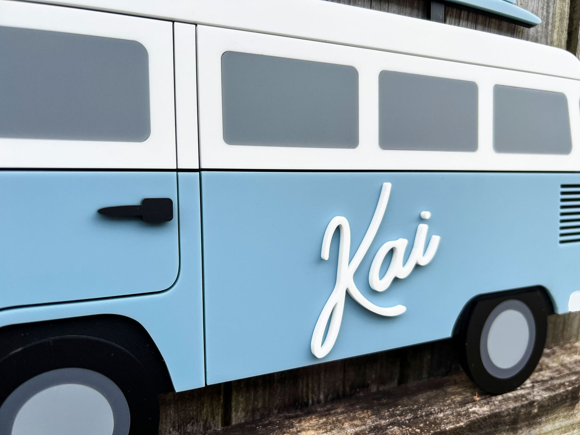 Light blue close up of a beach bus with 'Kai' written on the side.