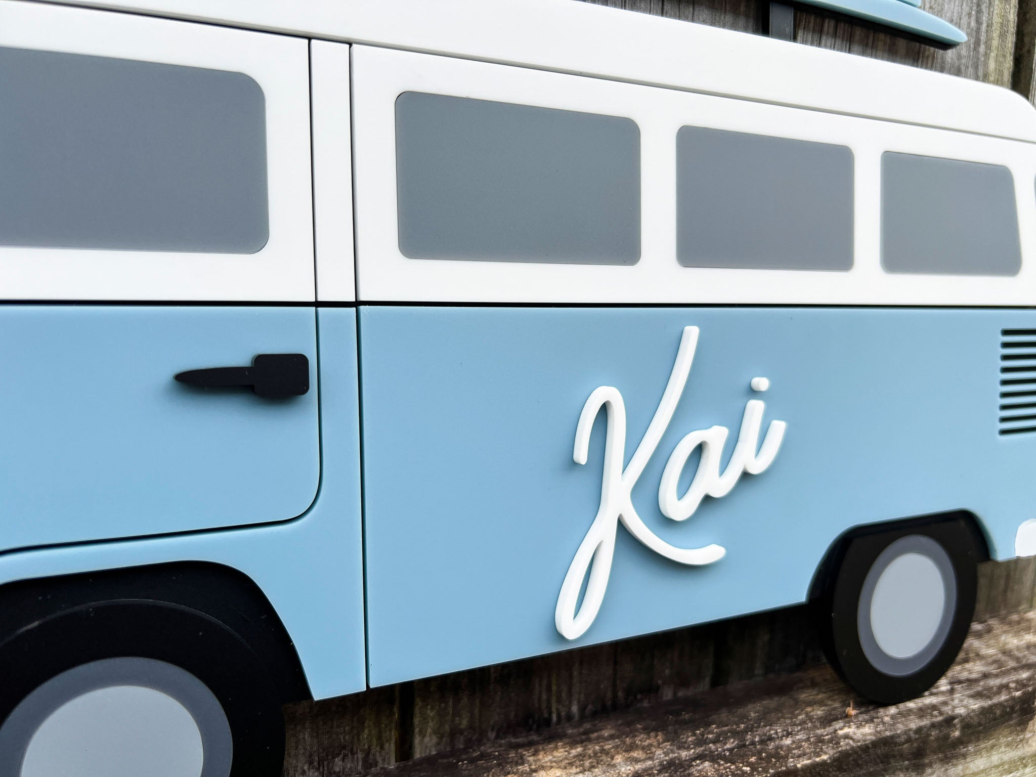 Light blue close up of a beach bus with 'Kai' written on the side.