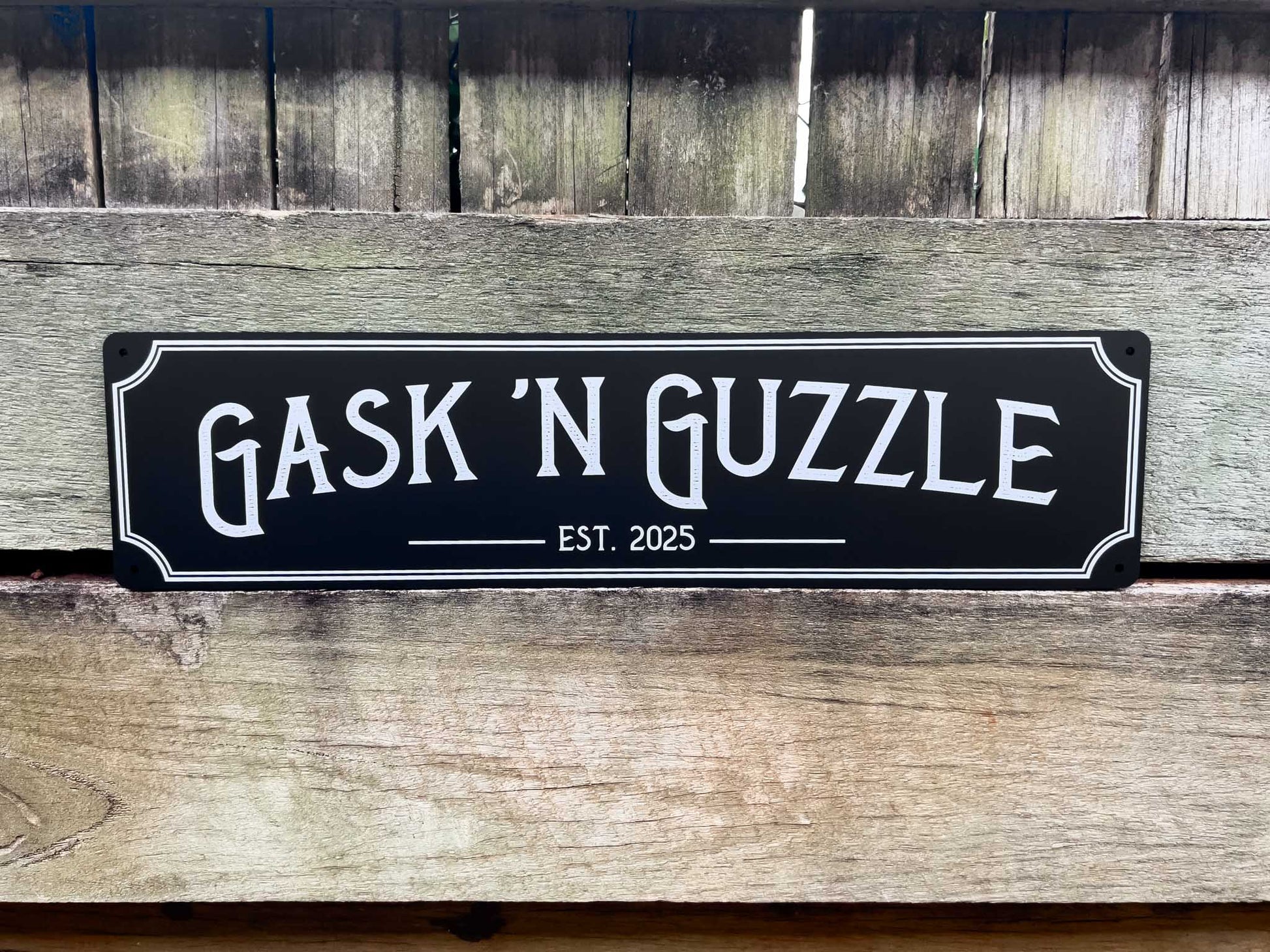 Decorative personalised bar sign with 'Gask 'N Guzzle' text on a wooden background