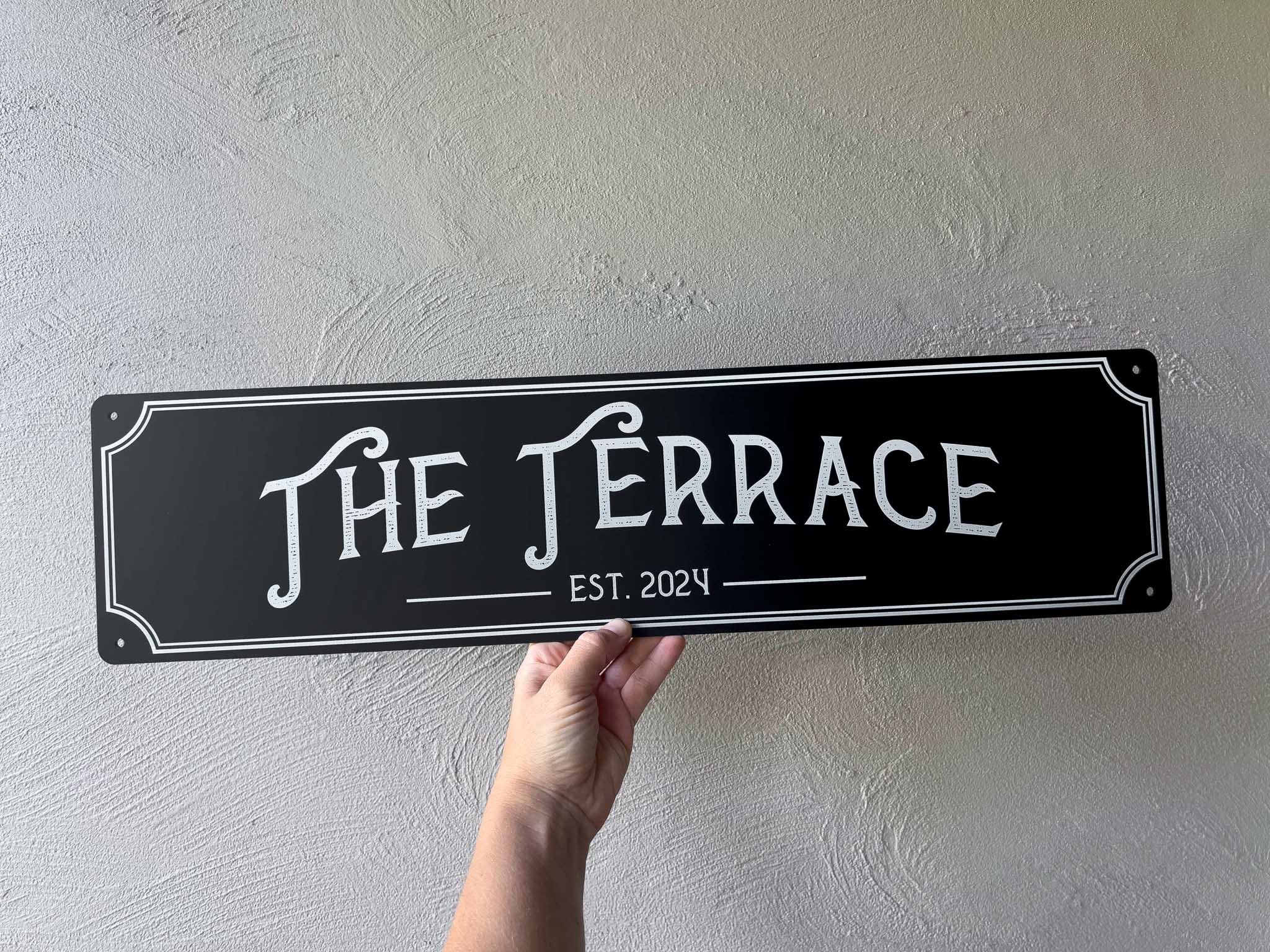 Personalised black and white textured destressed font that says 'The Terrace Est. 2024'.