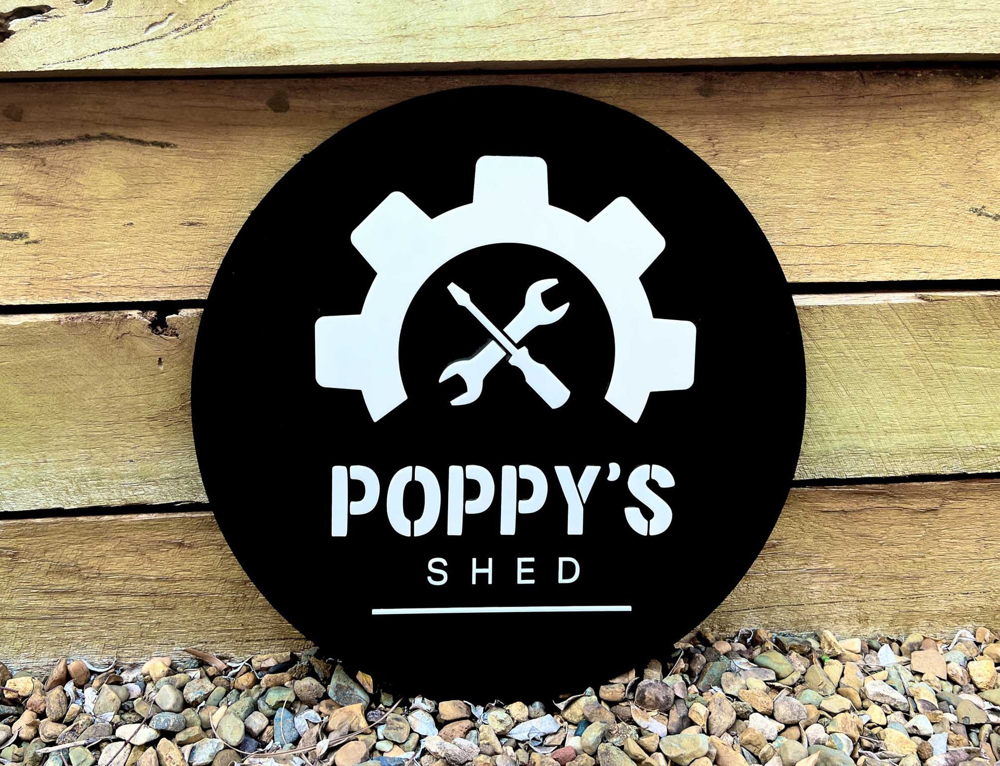 Custom round 'Poppy's Shed' sign in black and white with a screwdriver and spanner.