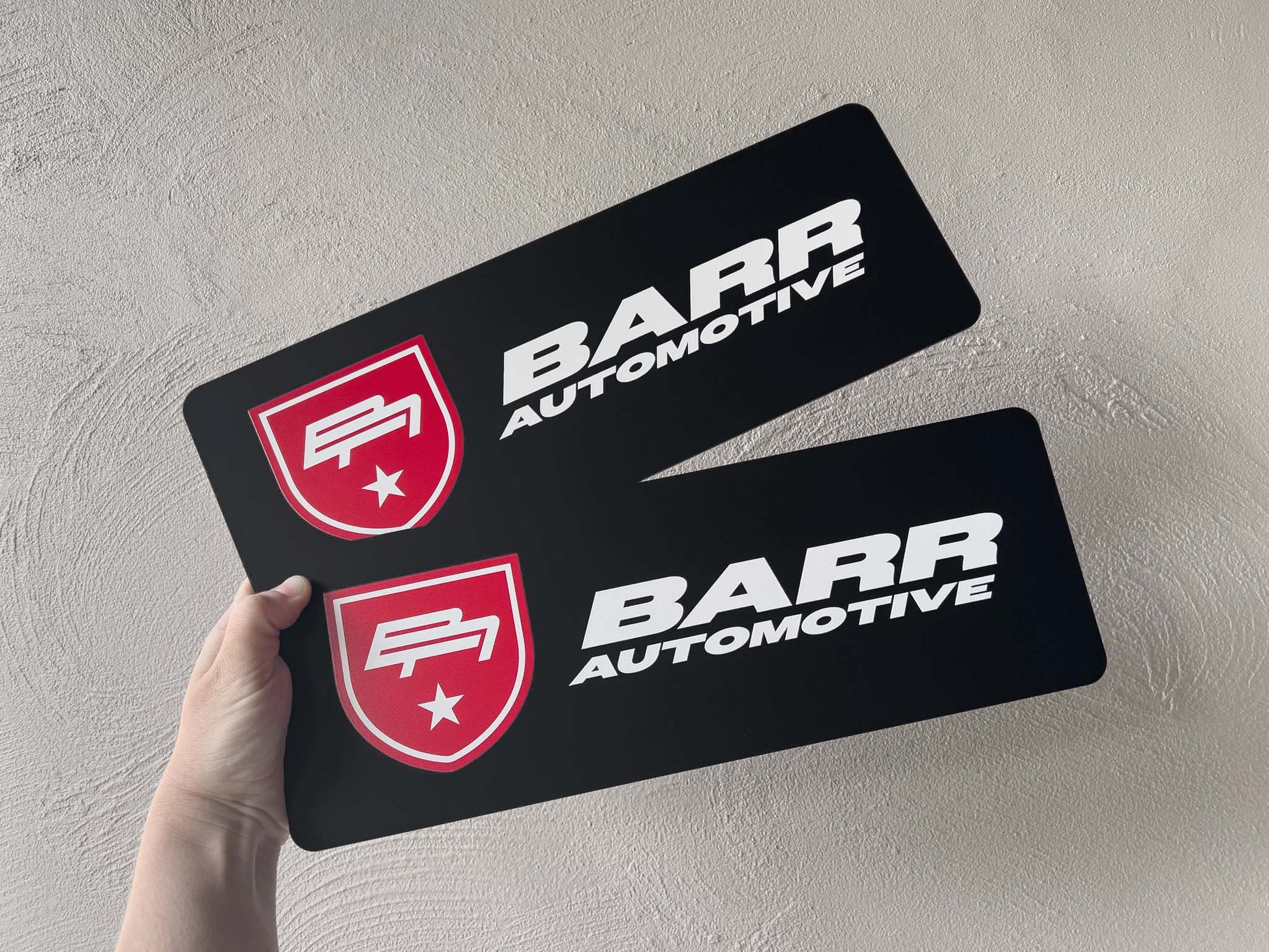 Two black custom printed logo plates with 'Barr Automotive' UV printed onto them.