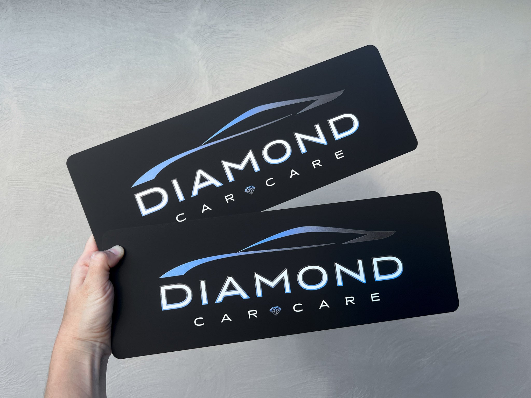 Two black Diamond Car Care logo plates UV printed in white and blue.