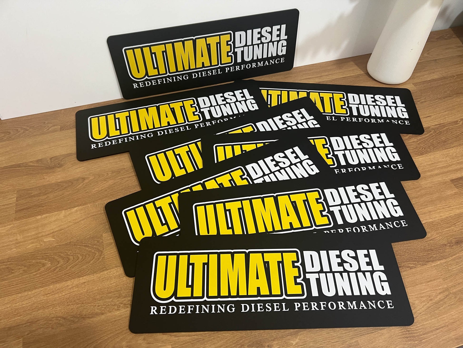 Collection of 'Ultimate Diesel Tuning' custom printed logo plates sitting on a desk.