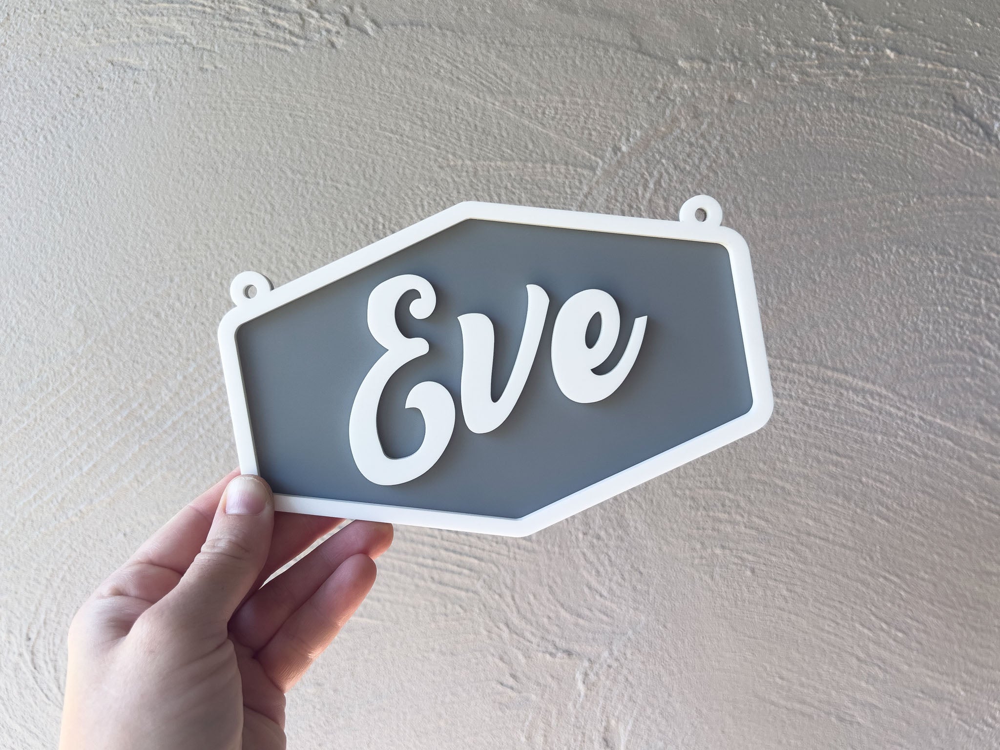 Hand holding a hexagonal sign with 'Eve' on a plain background | Coji Designs