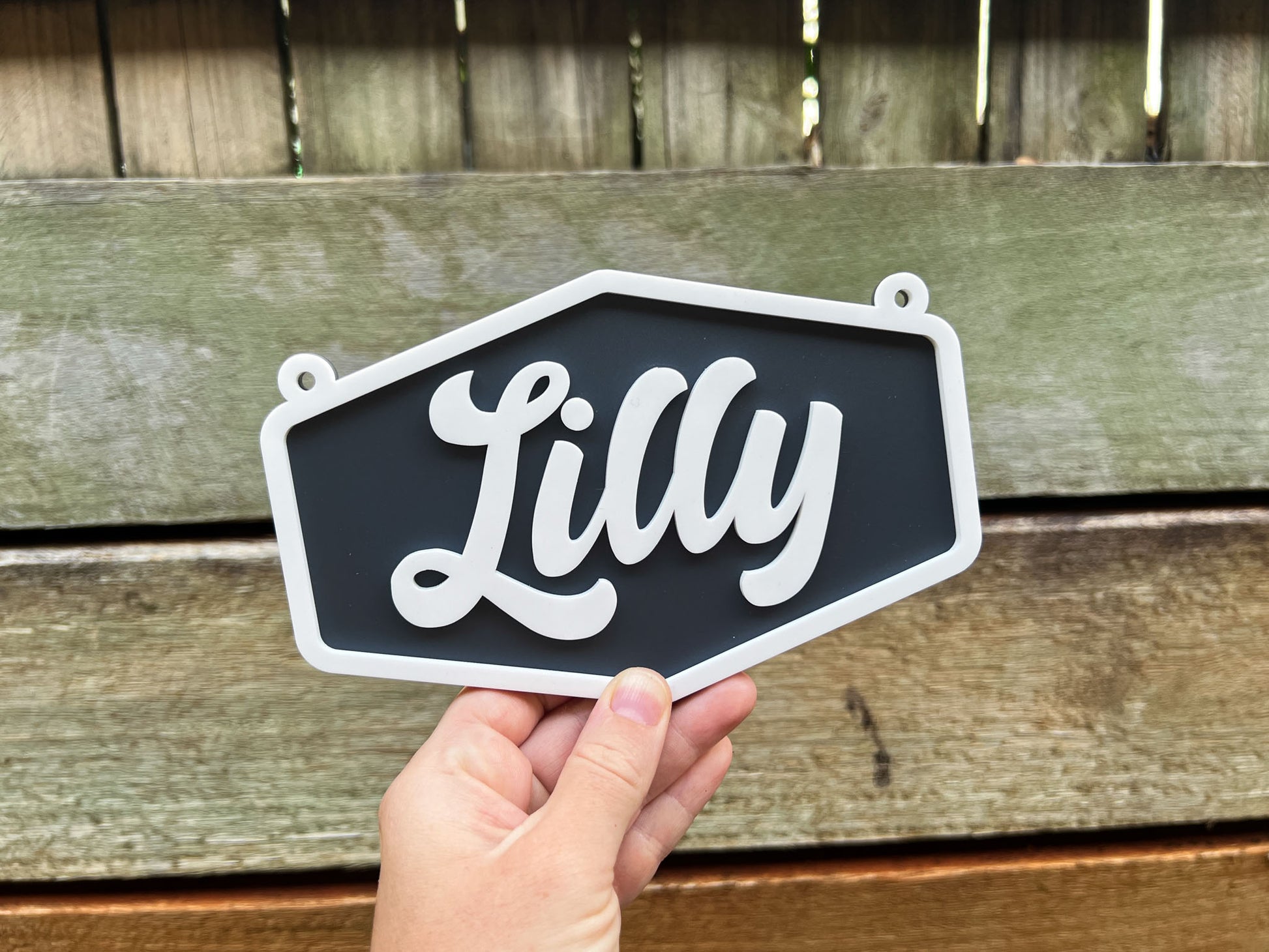 Hand holding a sign with 'Lilly' on it against a wooden background | Coji Designs