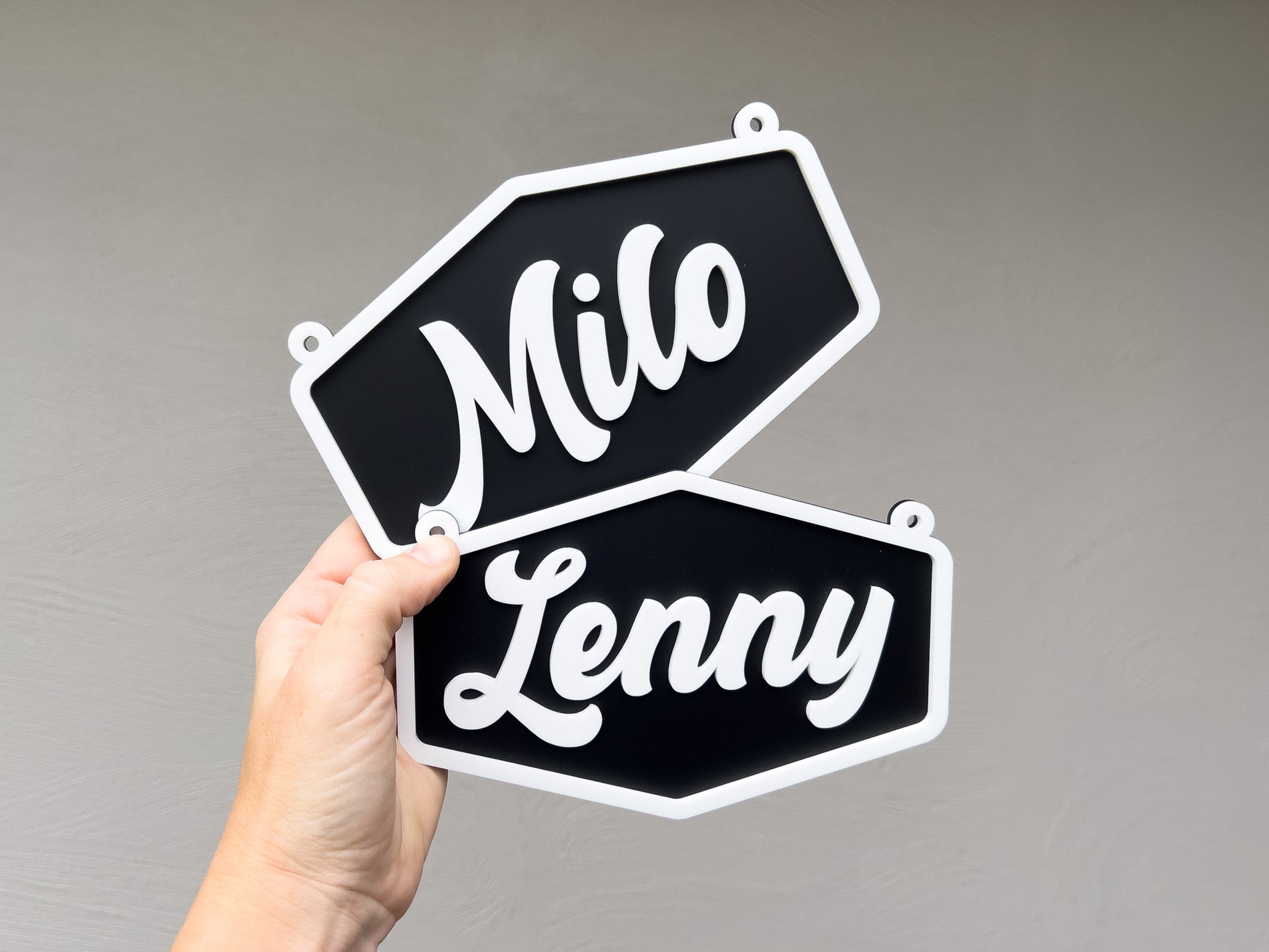 Two black hexagonal signs with 'Milo' and 'Lenny' text held against a gray background | Coji Designs