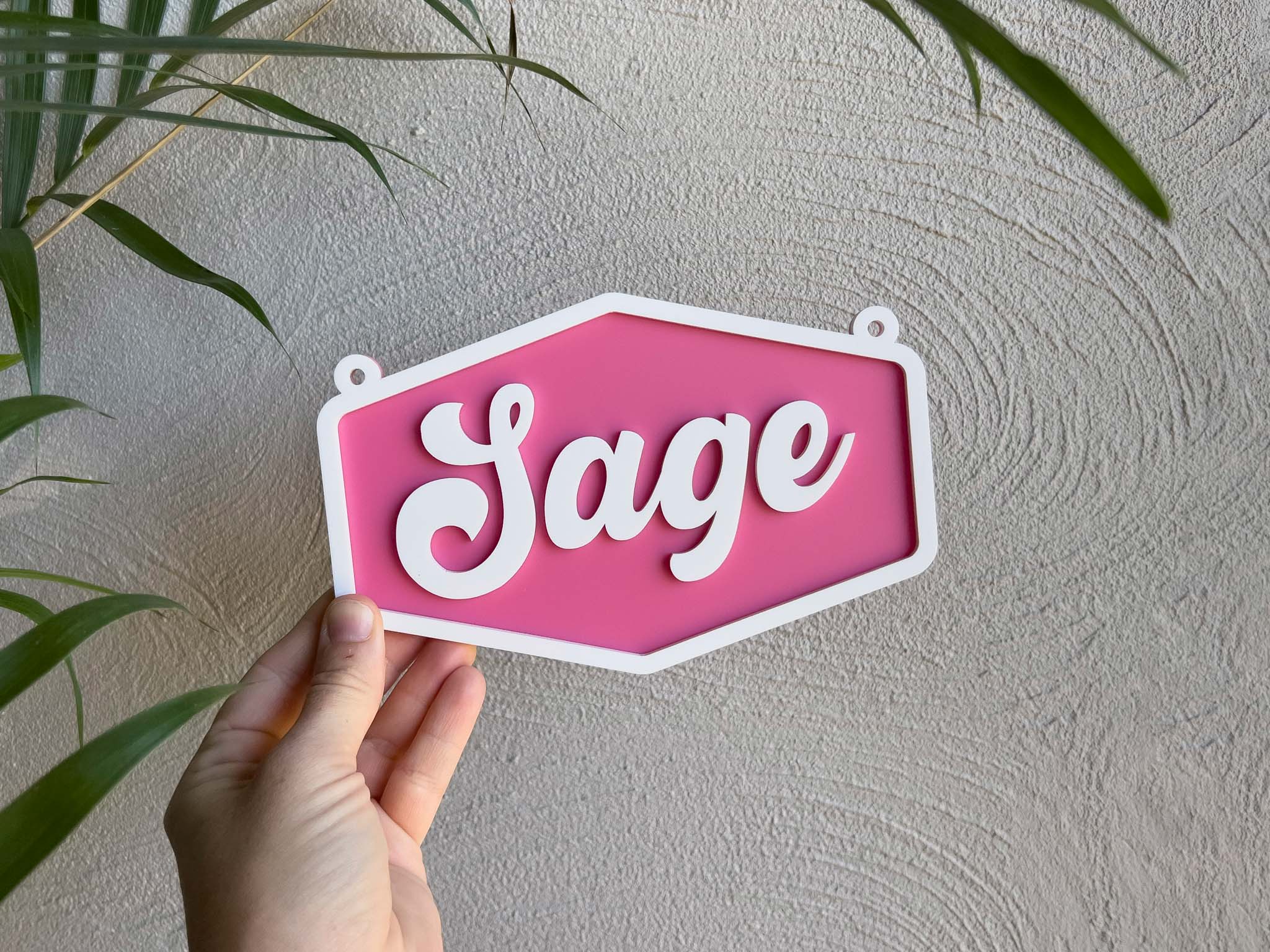 Hand holding a pink sign with 'Sage' on a light background | Coji Designs