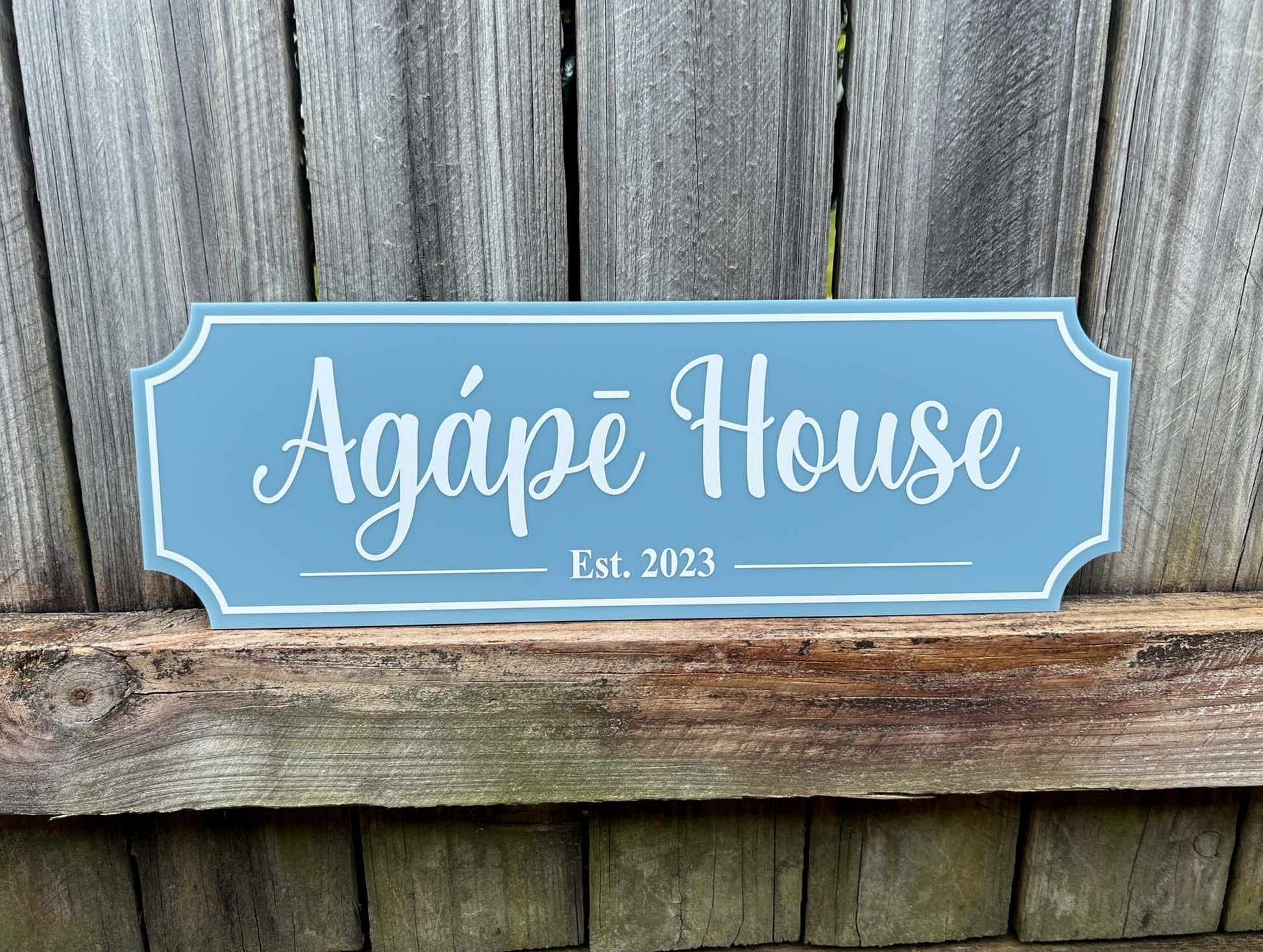 Custom UV printed acrylic traditional classic style sign that says 'Agape House Est. 2023' on a blue sign with white text.