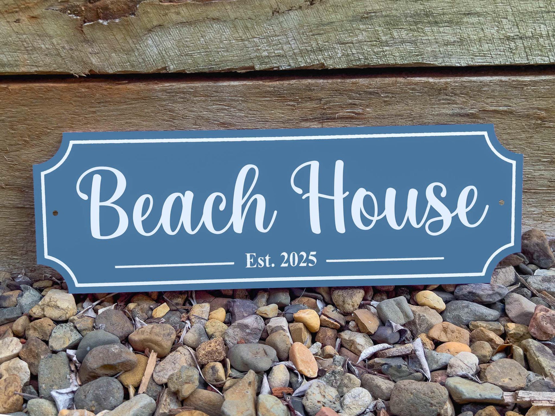 A deep sea blue acrylic sign with white cursive text that reads 'Beach House Est. 2025'.