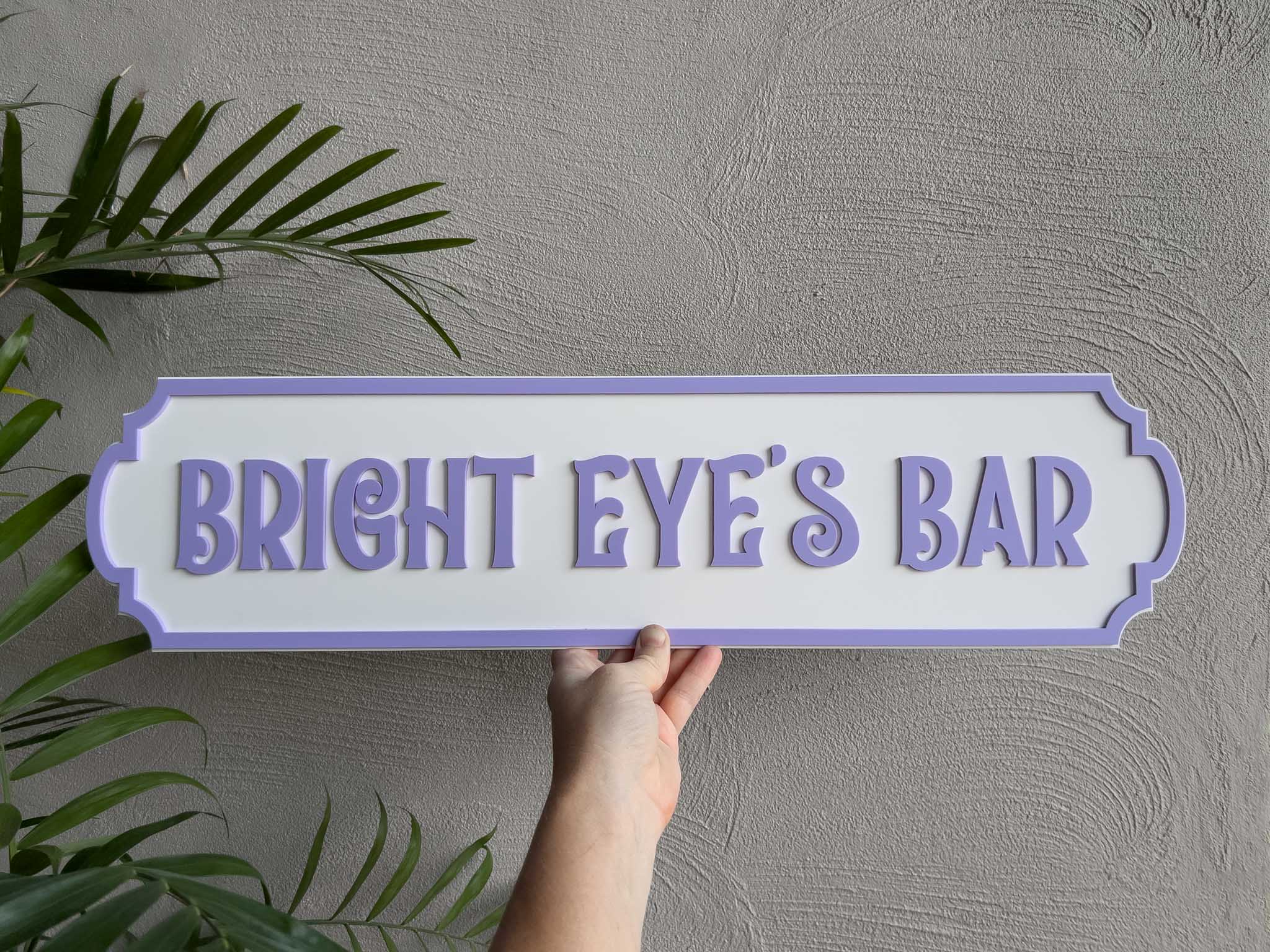 Tropical purple and white bar sign that say 'Bright Eye's Bar'.