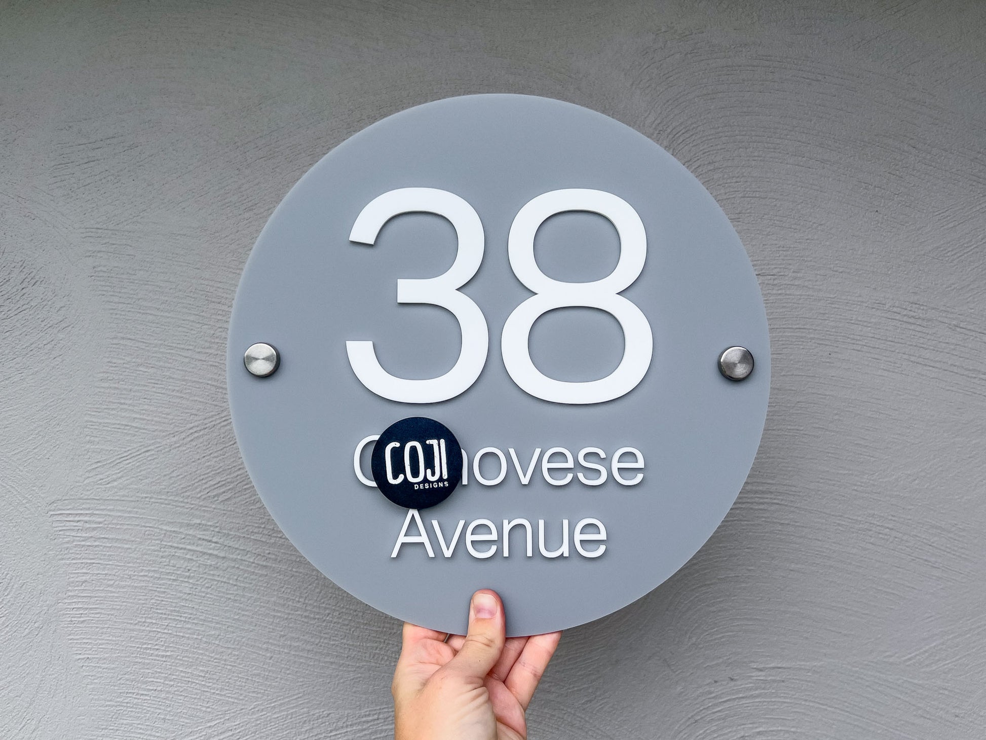 Personalised round house number sign with the number '38' in white on a grey acrylic sign.
