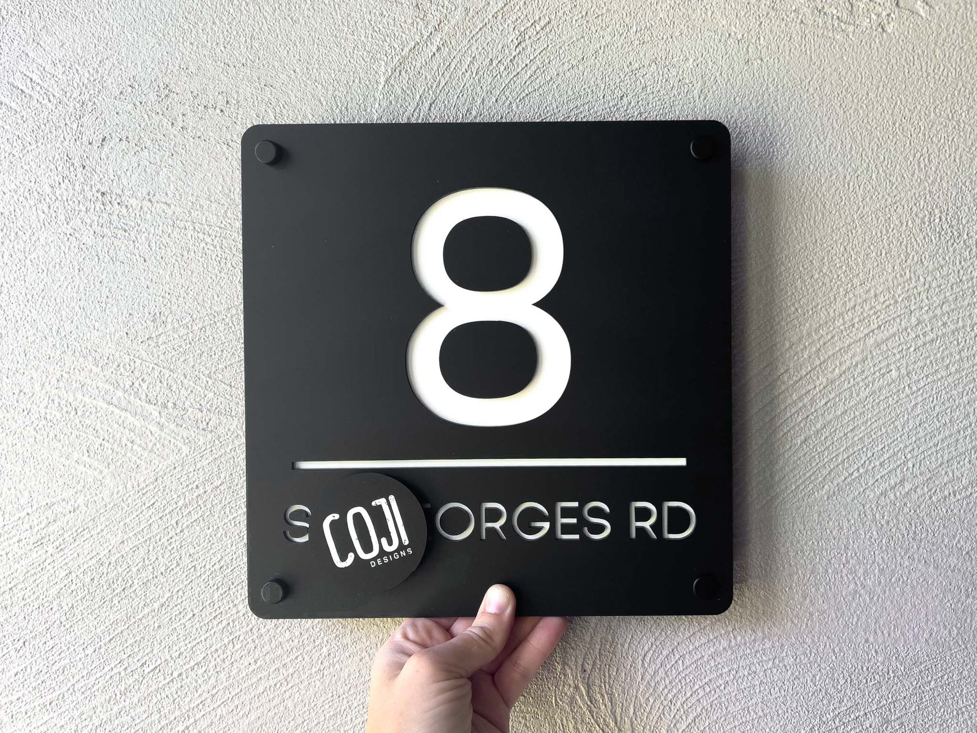 Black and white house number sign with the number '8' mounted to a wall