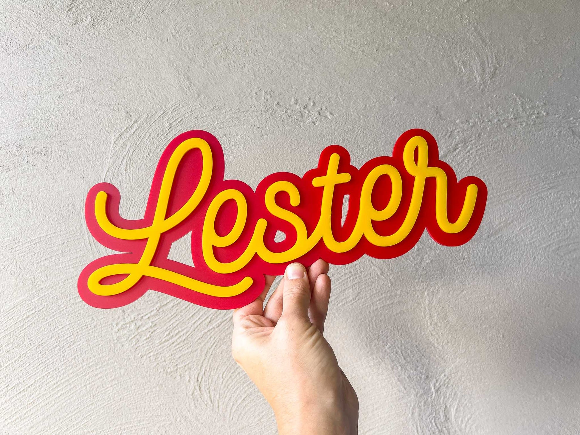 Swirly sunset vibe layered name plaque that reads 'Lester' in red and yellow.